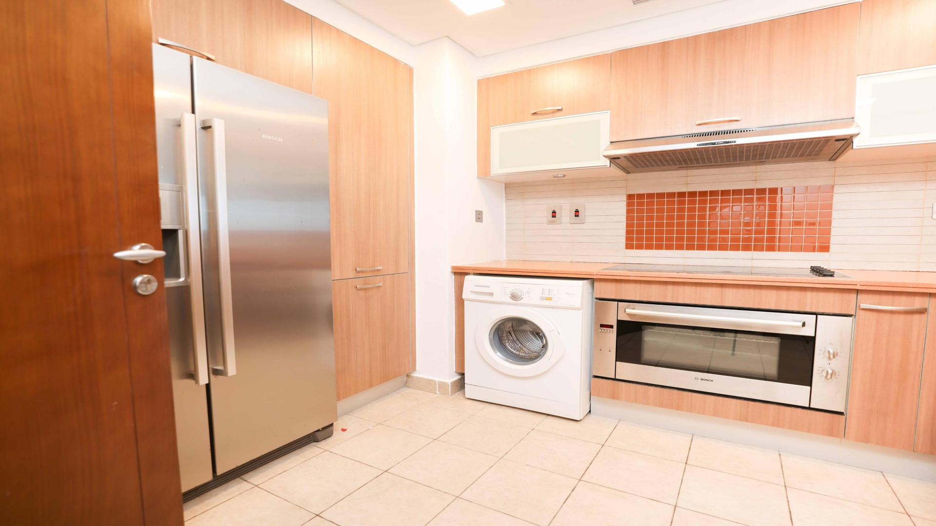 Modern kitchen in Palm Jumeirah apartment with stainless steel appliances and wood cabinetry