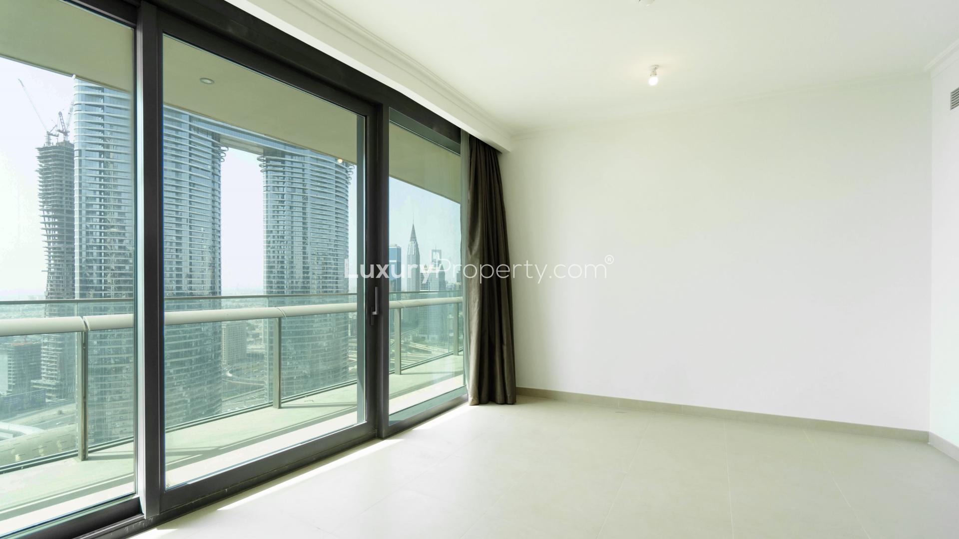 "Balcony view from Burj Vista apartment in Downtown Dubai, overlooking skyline and modern architecture.","Bright apartment interior with downtown Dubai skyline view through large windows, Burj Vista.",Modern kitchen in spacious Downtown Dubai apartment, featuring sleek cabinetry and stainless steel appliances