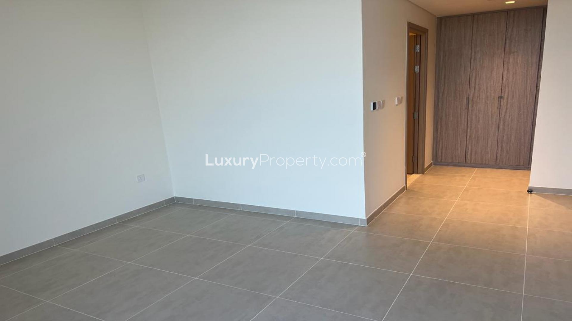 Empty apartment room with large window showcasing stunning Dubai Creek Harbour view