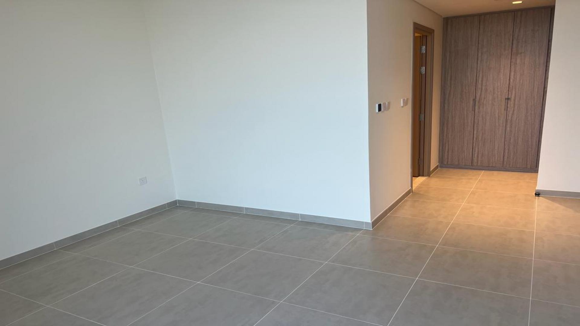 Empty apartment room with large window showcasing stunning Dubai Creek Harbour view