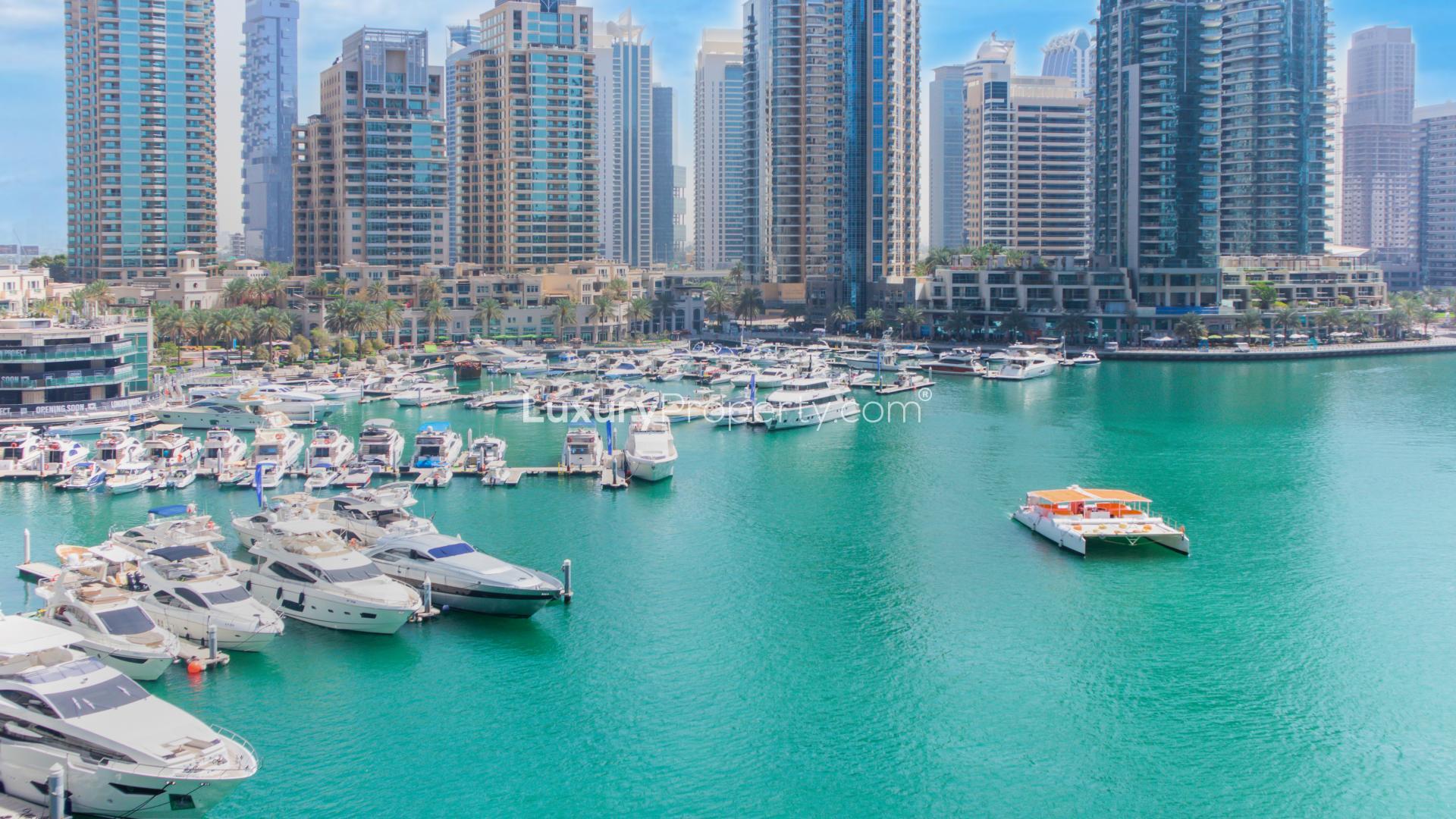 Alt text: "Cayan Tower exterior view, deluxe two-bedroom apartment for rent in Dubai Marina.",Dubai Marina view with yachts near Cayan Tower, deluxe two-bedroom apartment for rent