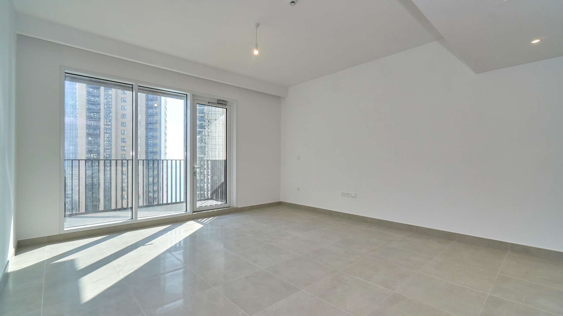 High-floor empty living room in Creek Horizon apartment, Dubai Creek Harbour, with balcony view