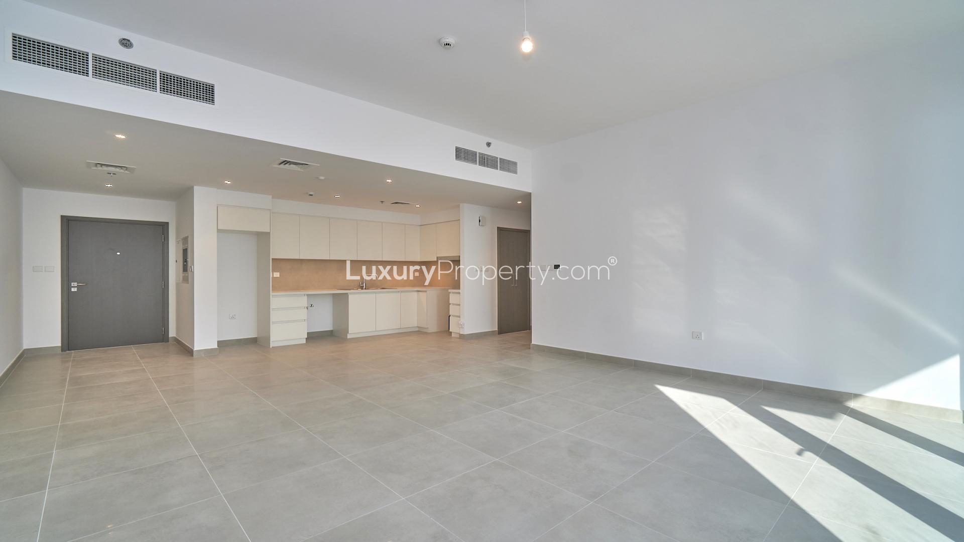 Empty creek-facing apartment living room with large windows in Creek Horizon