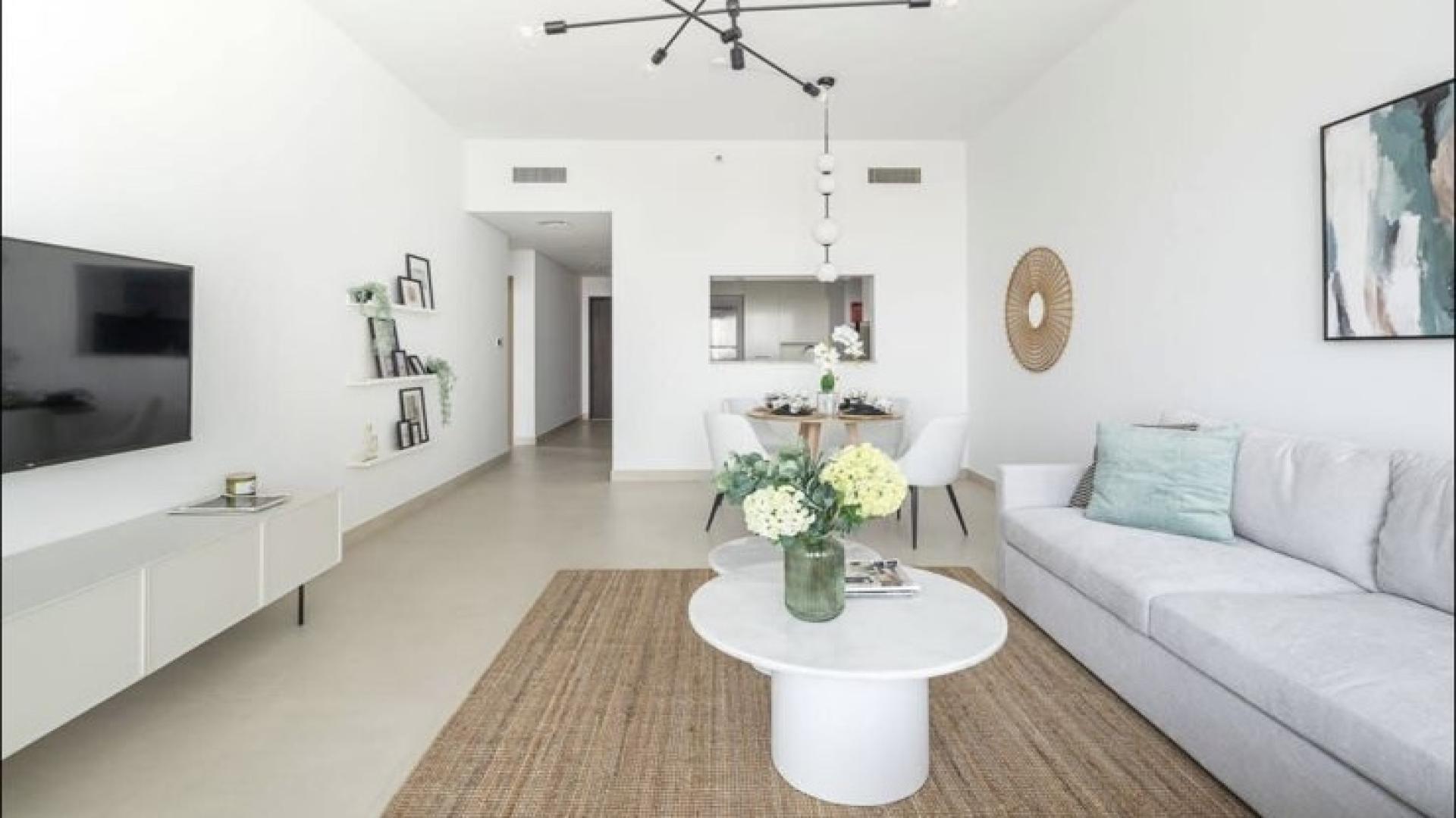 Modern living room with large sofa, TV, and balcony view in Zabeel apartment
