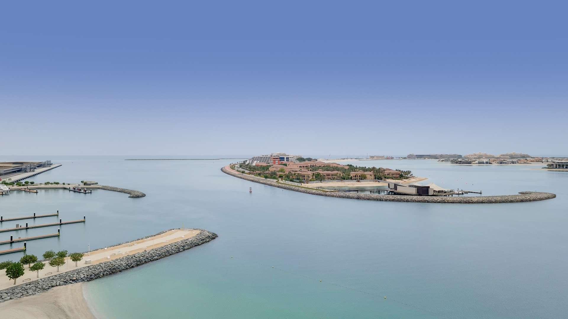 "Bright apartment interior with floor-to-ceiling windows and stunning sea views at Emaar Beachfront.",Aerial view of Emaar Beachfront with serene sea and Palm Jumeirah in Dubai Harbour