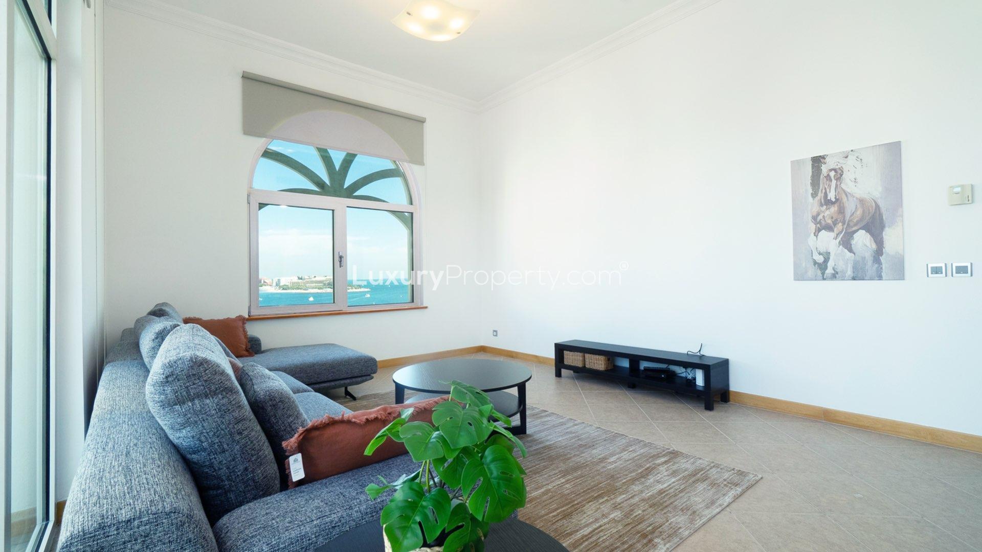 "Palm Jumeirah apartment balcony with sea views, Shoreline Apartments, 3-bedroom rental.",Palm Jumeirah apartment living room with sea view, modern furnishings, and wall art