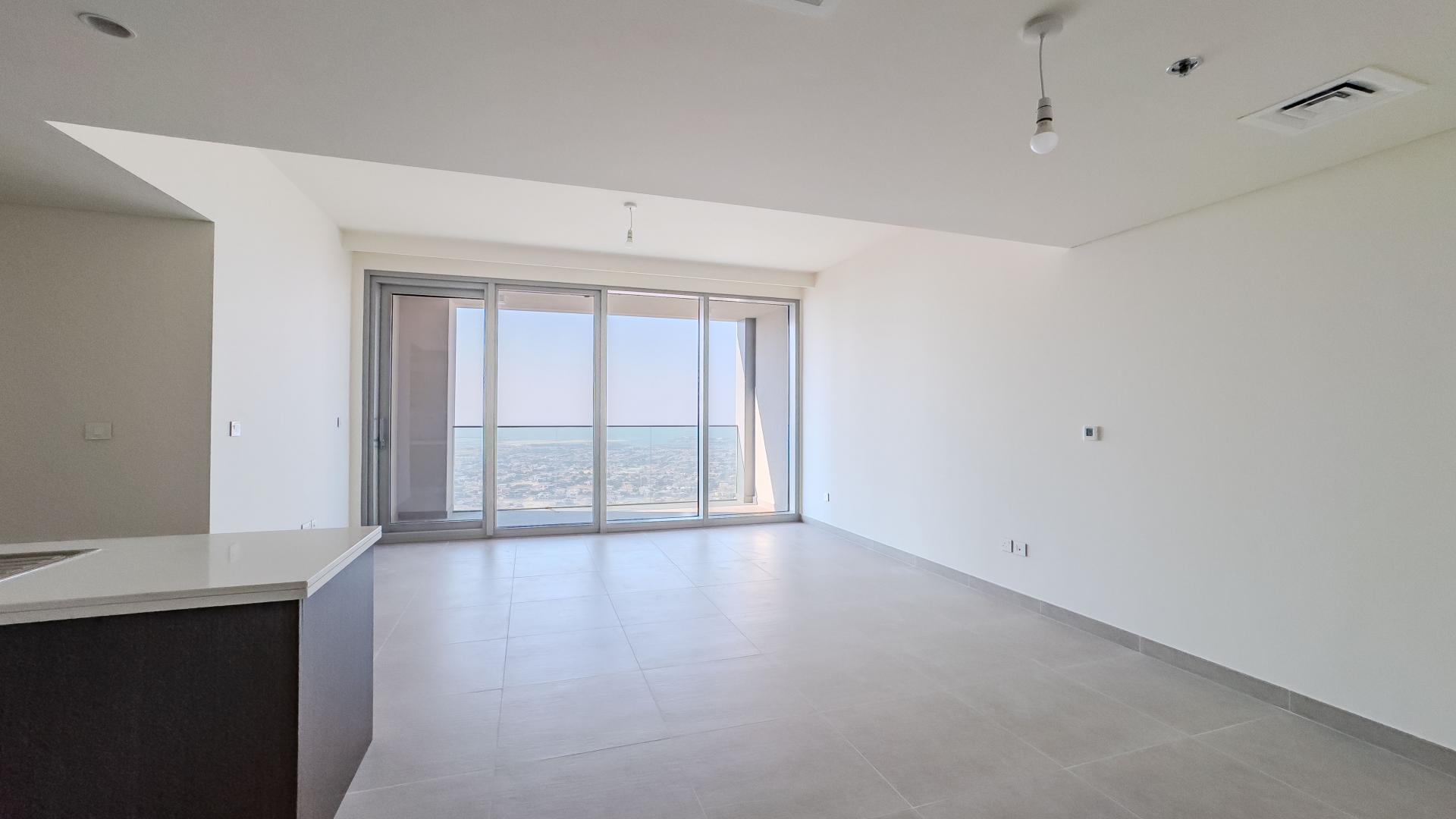 Empty high-rise apartment living room with floor-to-ceiling windows and sea view in Downtown Dubai