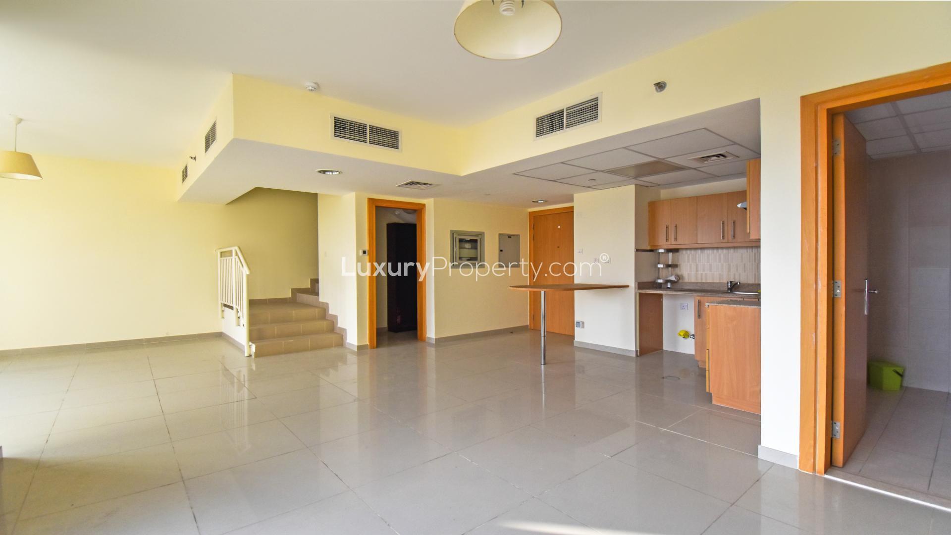 Modern interior of 2-bedroom duplex in Jumeirah Village Triangle, featuring open kitchen and staircase