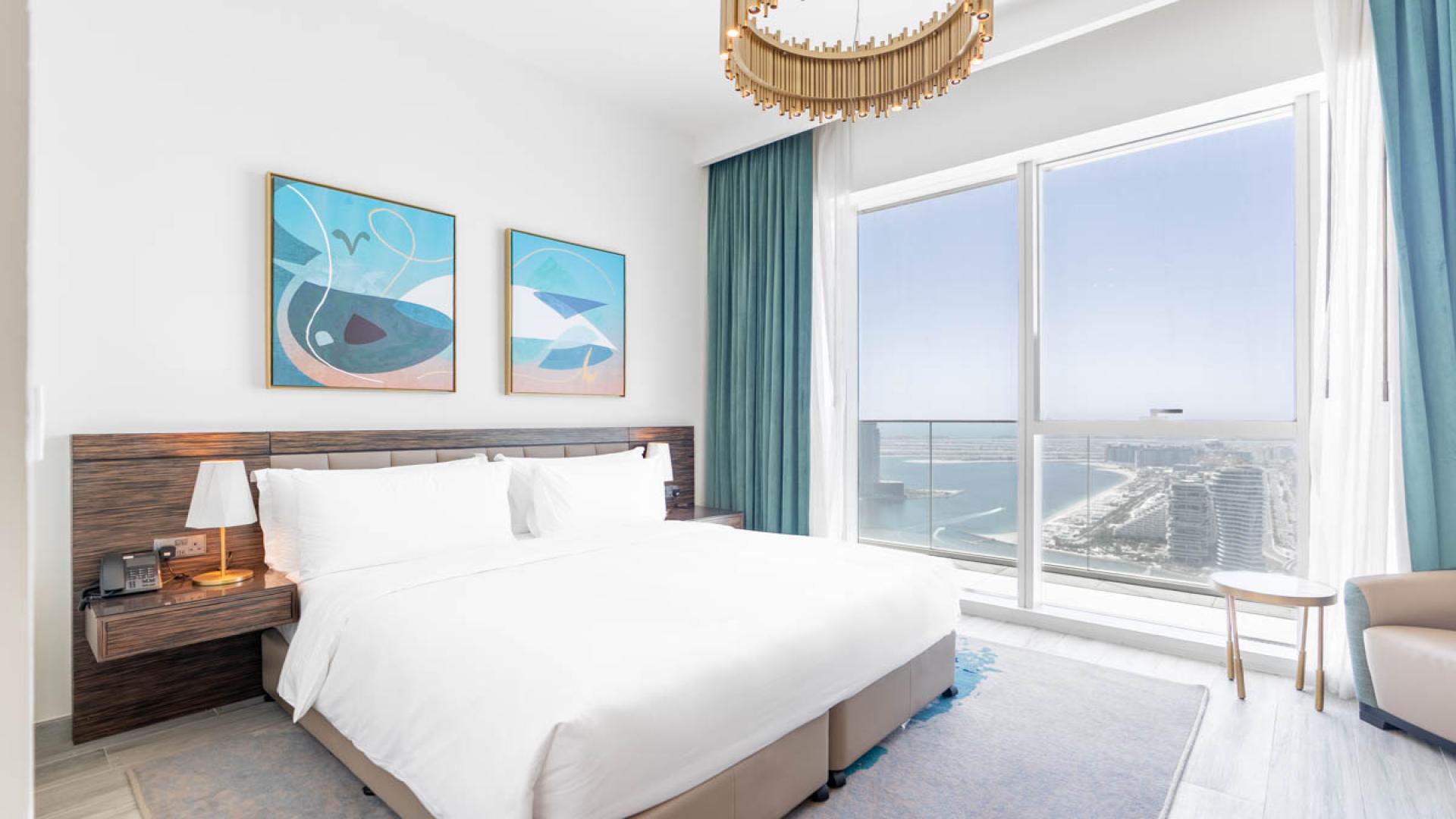 Modern Dubai Media City apartment living room with ocean view, blue sofas, and chic decor
