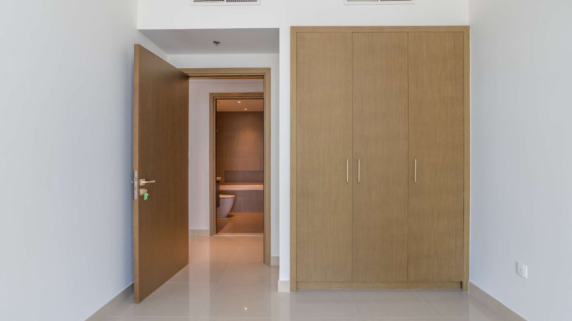 Empty bedroom with built-in wardrobe and bathroom view in Dubai Creek Harbour apartment