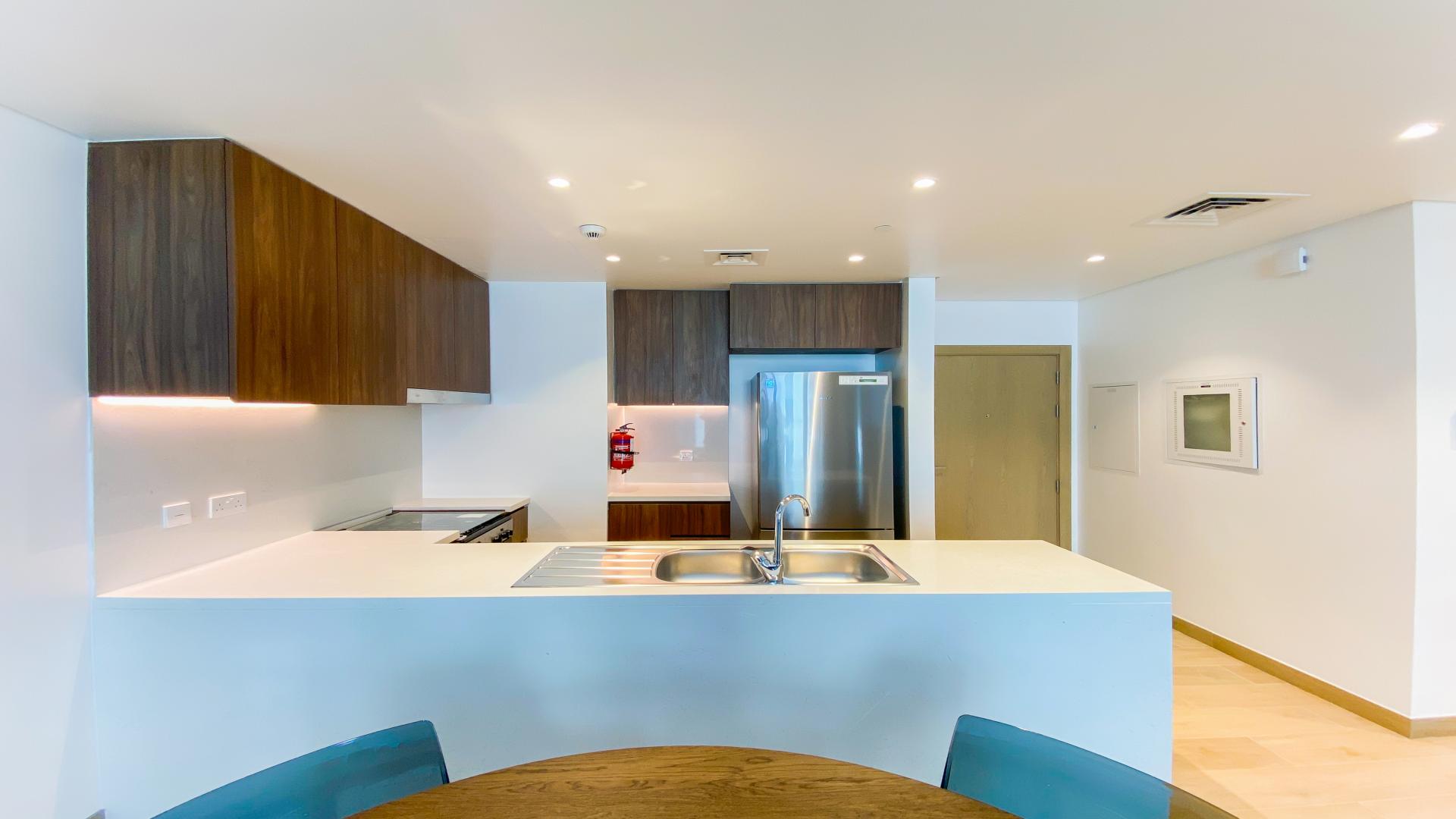 Modern kitchen in 2-bedroom apartment, Porte De La Mer, Dubai, with sleek wood cabinets