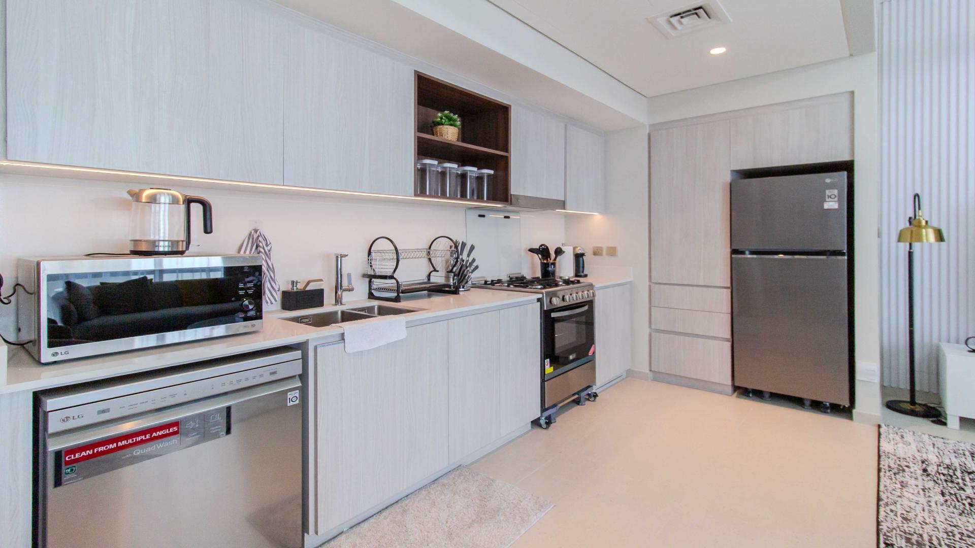 Modern living room in high-floor apartment, Dubai Creek Harbour, with stylish furnishings and open kitchen