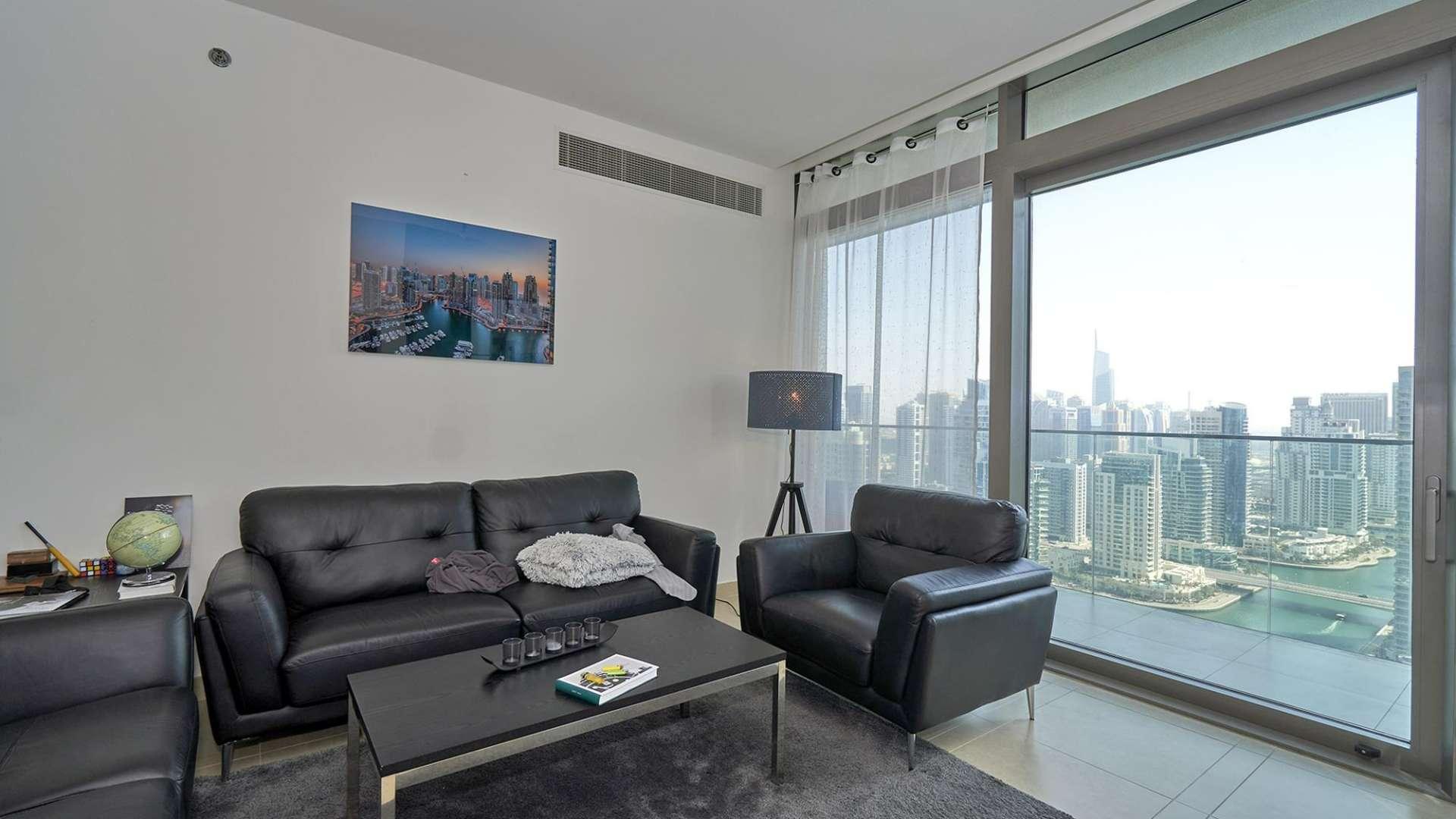 Living room in Marina Gate apartment with cityscape views, modern furnishings, and balcony access