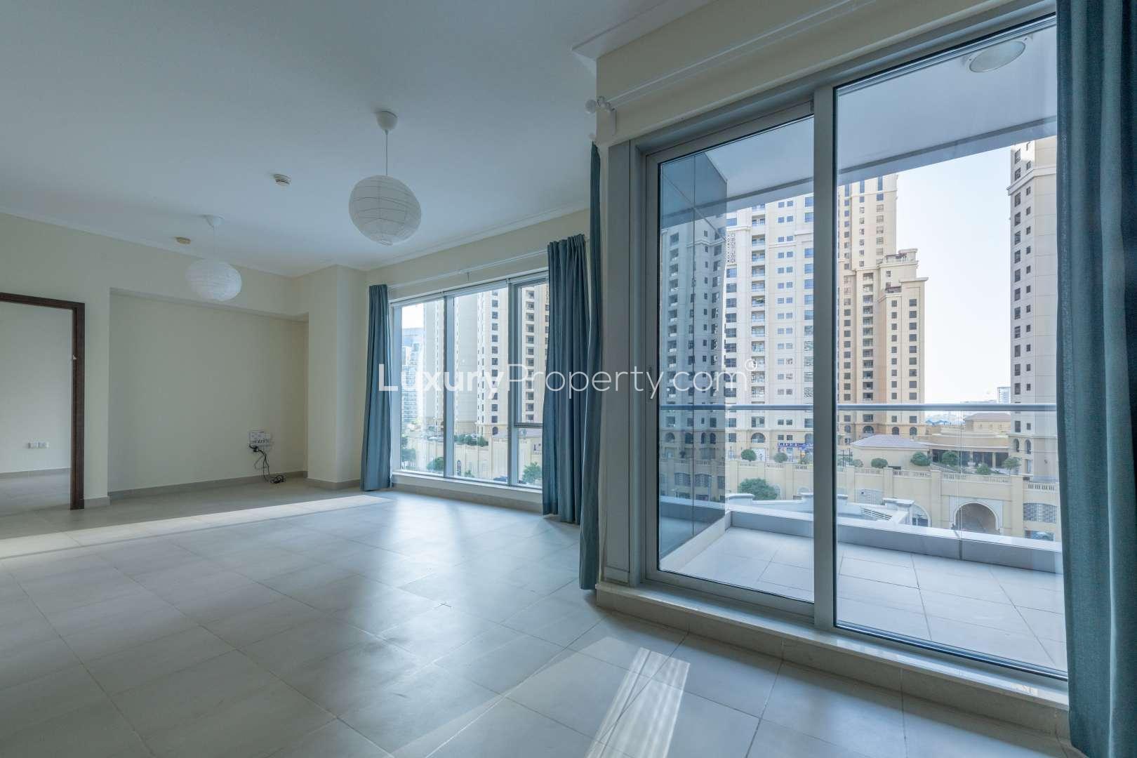 Bright living room in 2-bedroom Marina Promenade apartment with large windows and balcony view