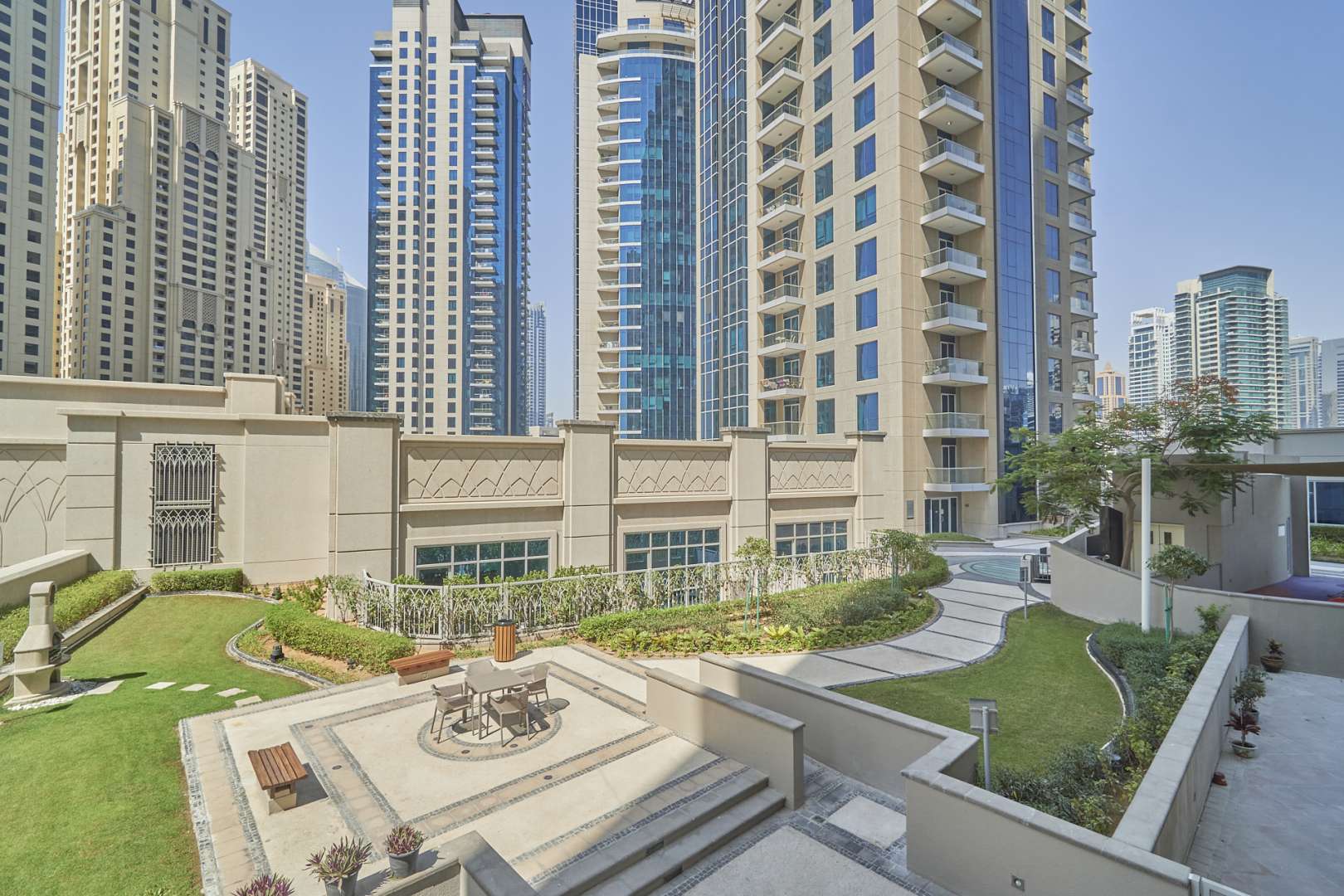 "Modern kitchen in spacious Marina Promenade apartment, granite countertops, wooden cabinets, Dubai Marina.",Exterior view of Marina Promenade apartment complex in Dubai Marina with garden area