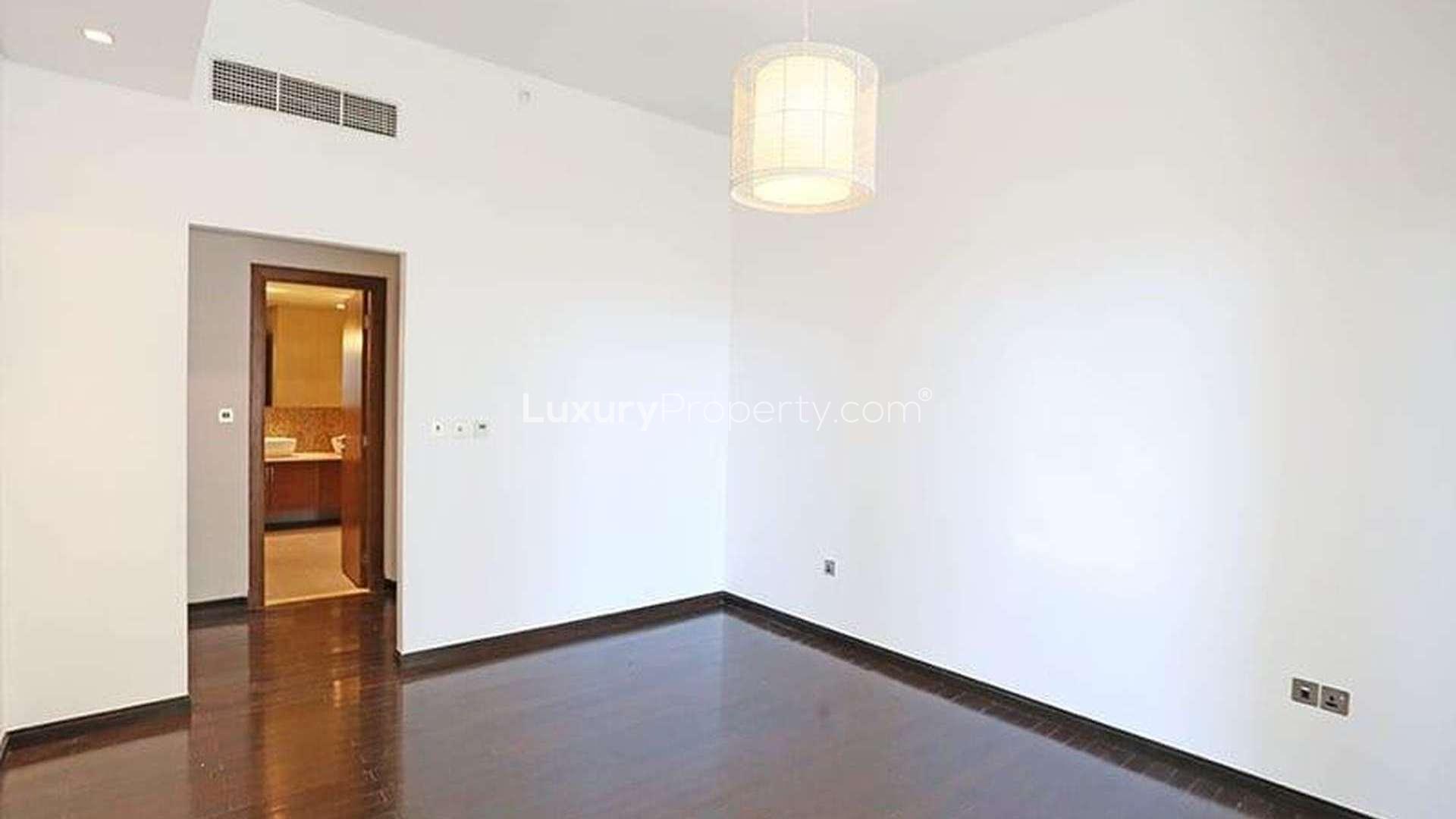 Modern kitchen in Palm Jumeirah apartment, featuring stainless steel fridge and wood cabinets