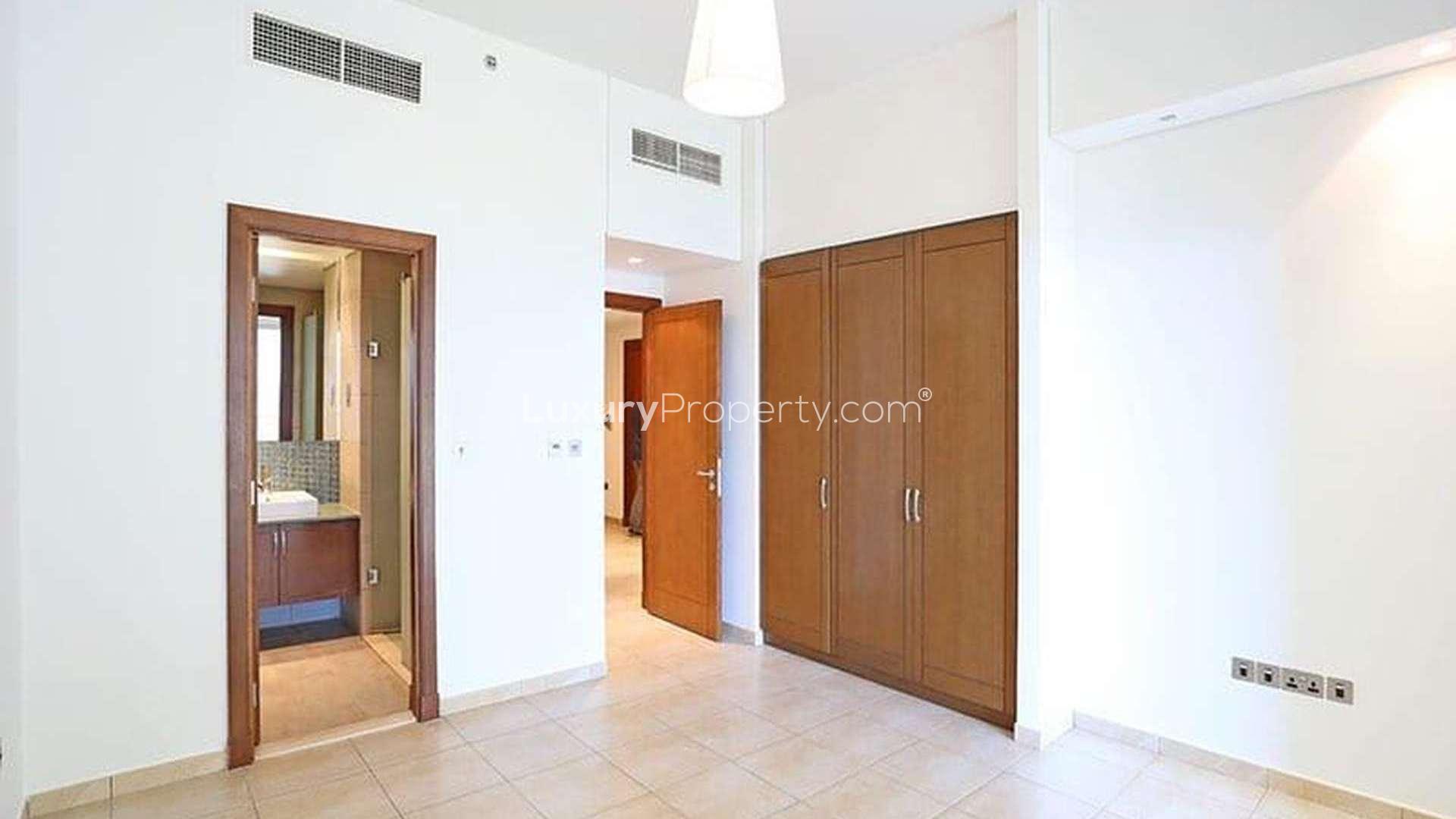 "Spacious bedroom with ensuite bathroom in Palm Jumeirah apartment, Marina Residences, for rent.",Empty room with wooden flooring in Palm Jumeirah apartment, Marina Residences, for rent