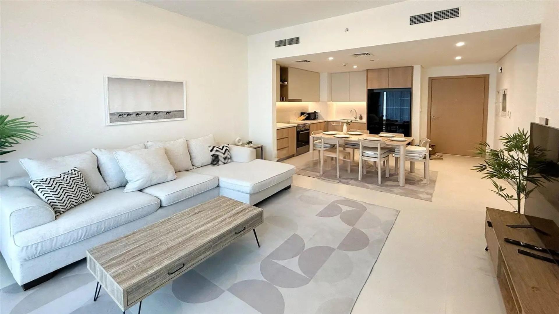 Modern living room in Dubai Creek Harbour apartment, featuring open kitchen and stylish furnishings