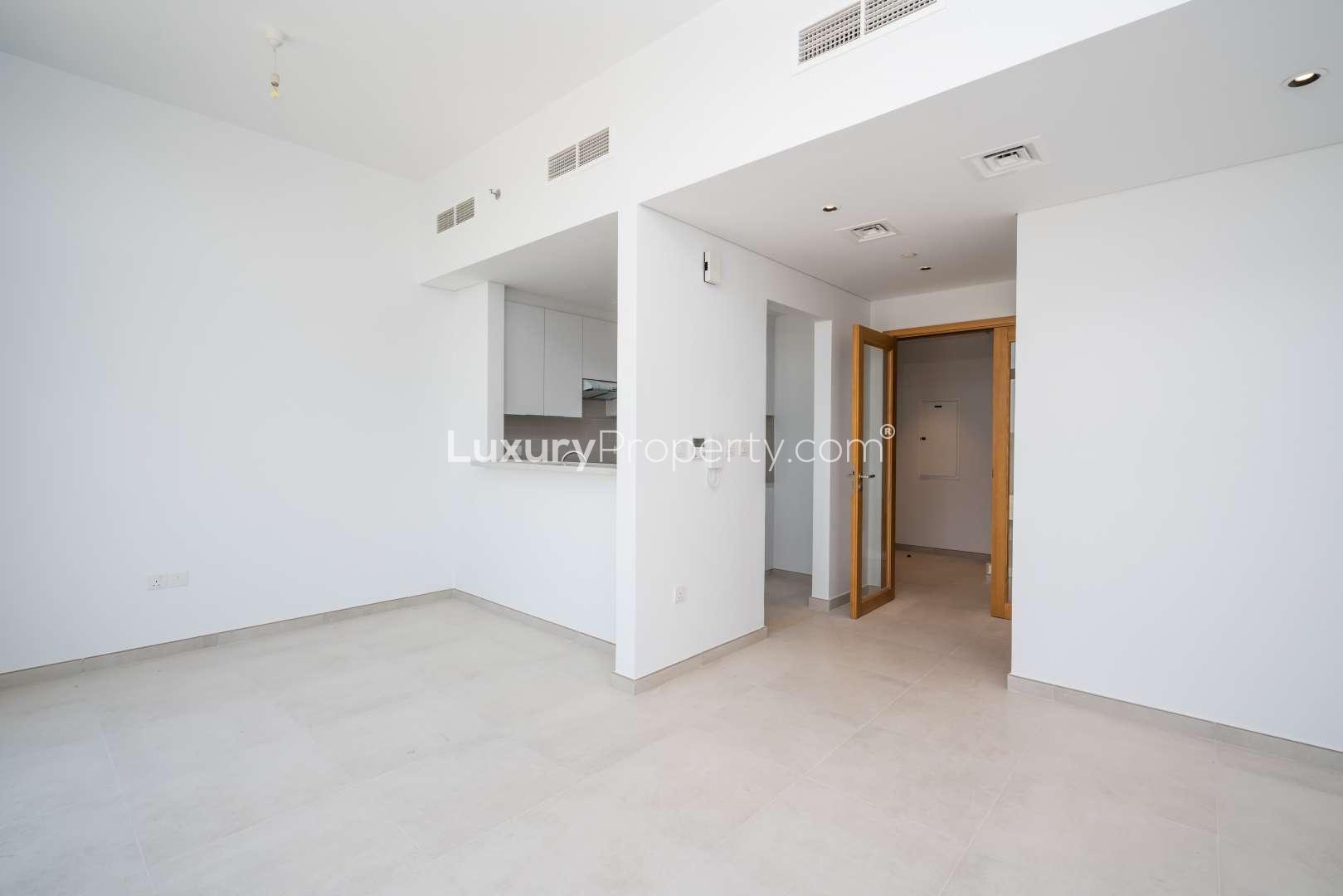 Empty living room in Mudon Views 2-bedroom apartment with open kitchen and wooden door