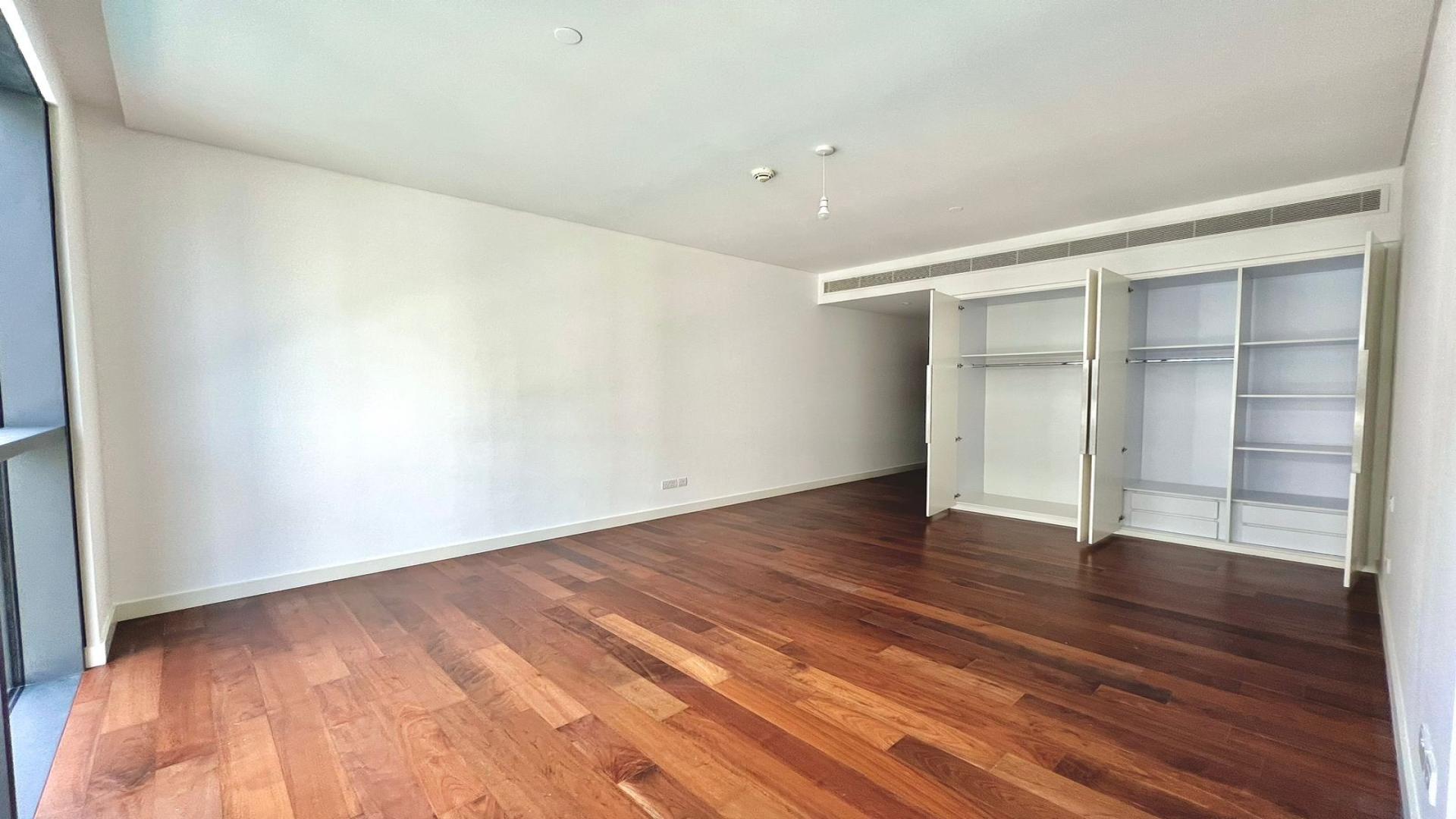 Empty bedroom with wooden floors and built-in closets in City Walk apartment, Building 13A