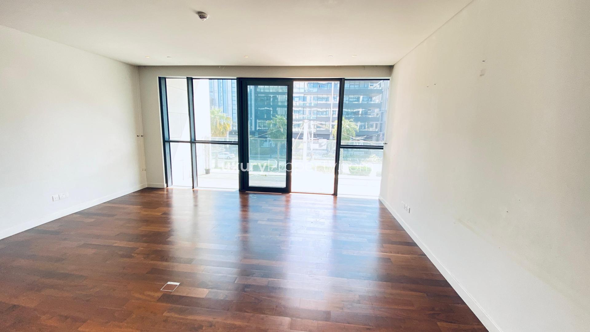 "Spacious City Walk apartment with large windows, hardwood floors, and Burj Khalifa views.",Empty living room with large window, hardwood floors in City Walk 2-bedroom apartment