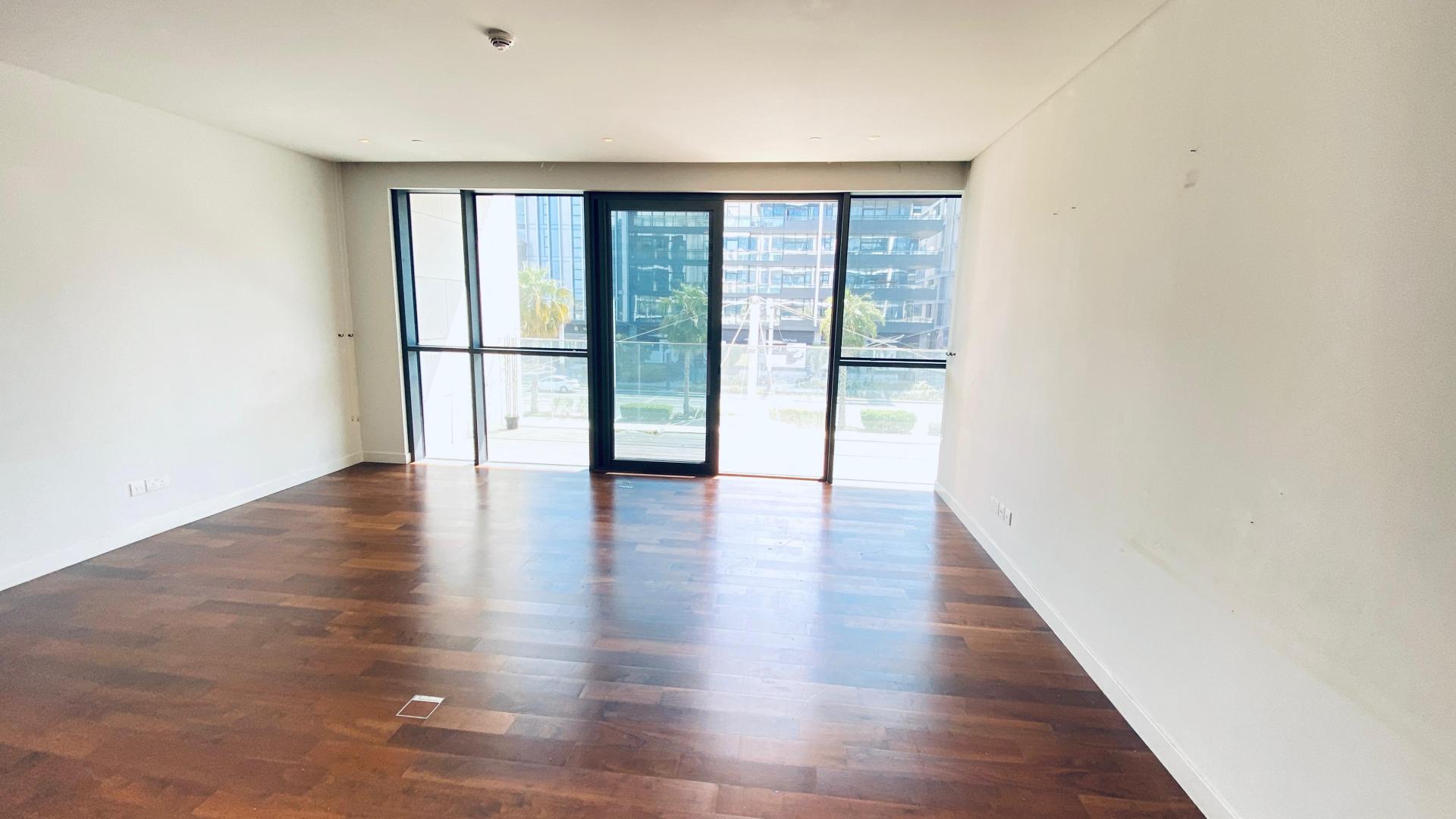 "Spacious City Walk apartment with large windows, hardwood floors, and Burj Khalifa views.",Empty living room with large window, hardwood floors in City Walk 2-bedroom apartment