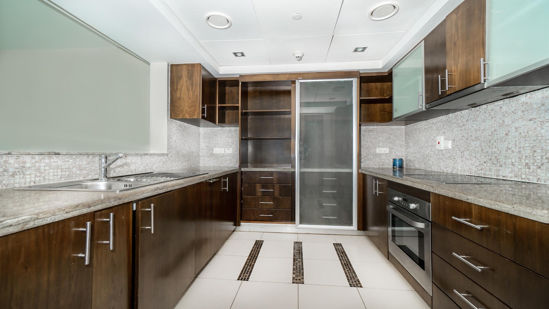 "Dubai Marina apartment balcony view overlooking water and skyline, Park Island community.",Modern kitchen with wooden cabinets in spacious Dubai Marina apartment for rent, Park Island