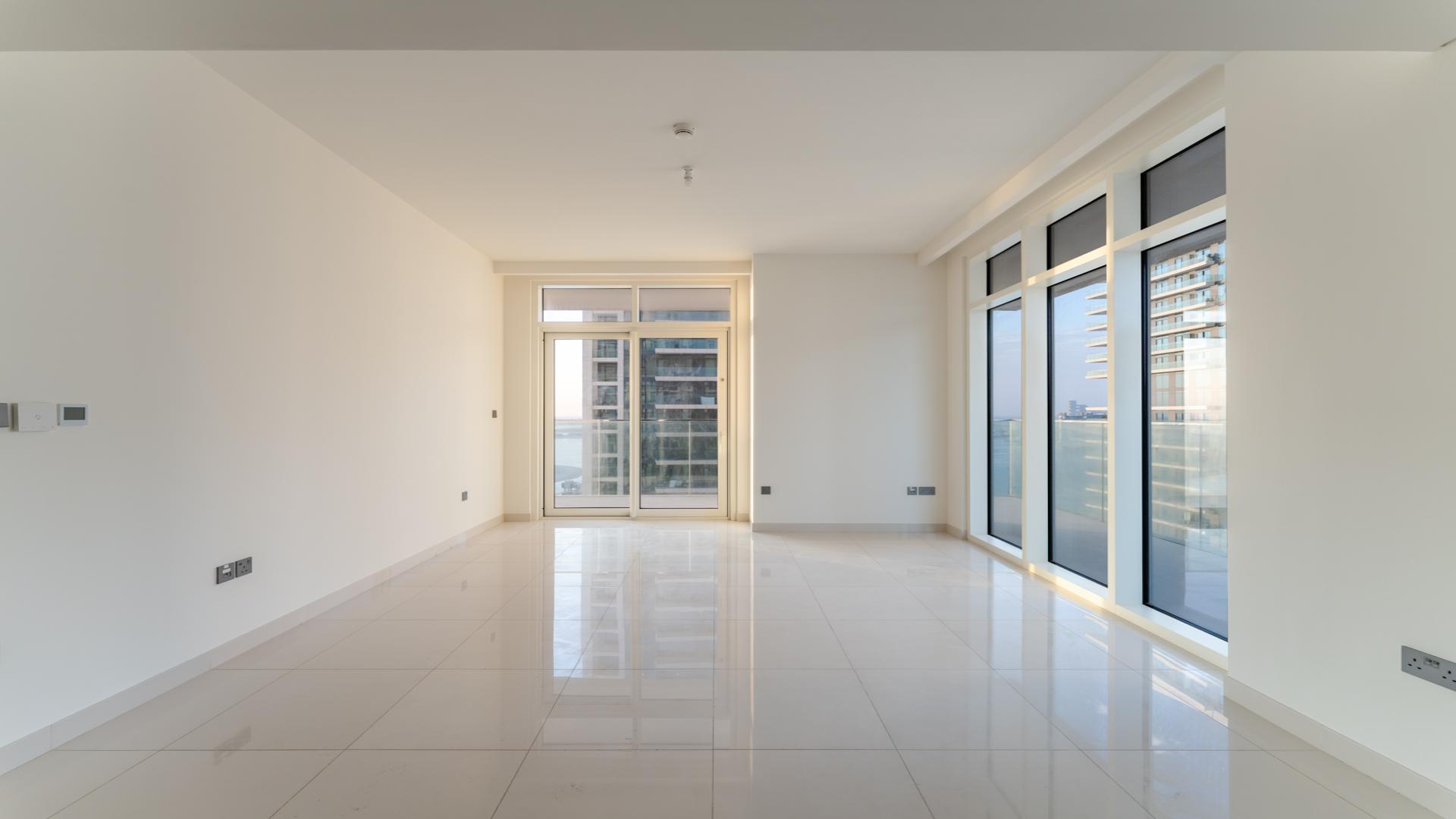 "Spacious balcony view in Emaar Beachfront apartment, Dubai Harbour, overlooking modern high-rise buildings.",Empty living room with large windows in Emaar Beachfront apartment, Dubai Harbour