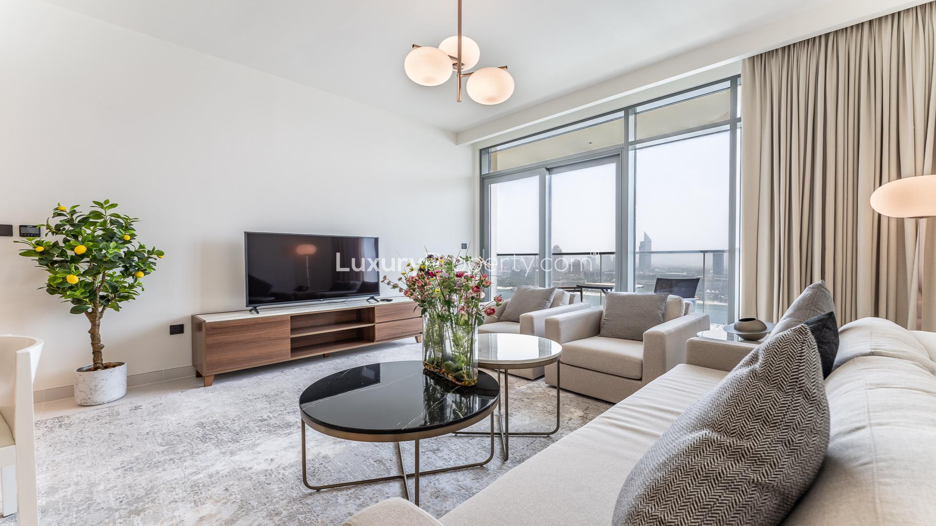 Modern living room in two-bedroom Dubai Harbour apartment, featuring sleek furniture and open kitchen