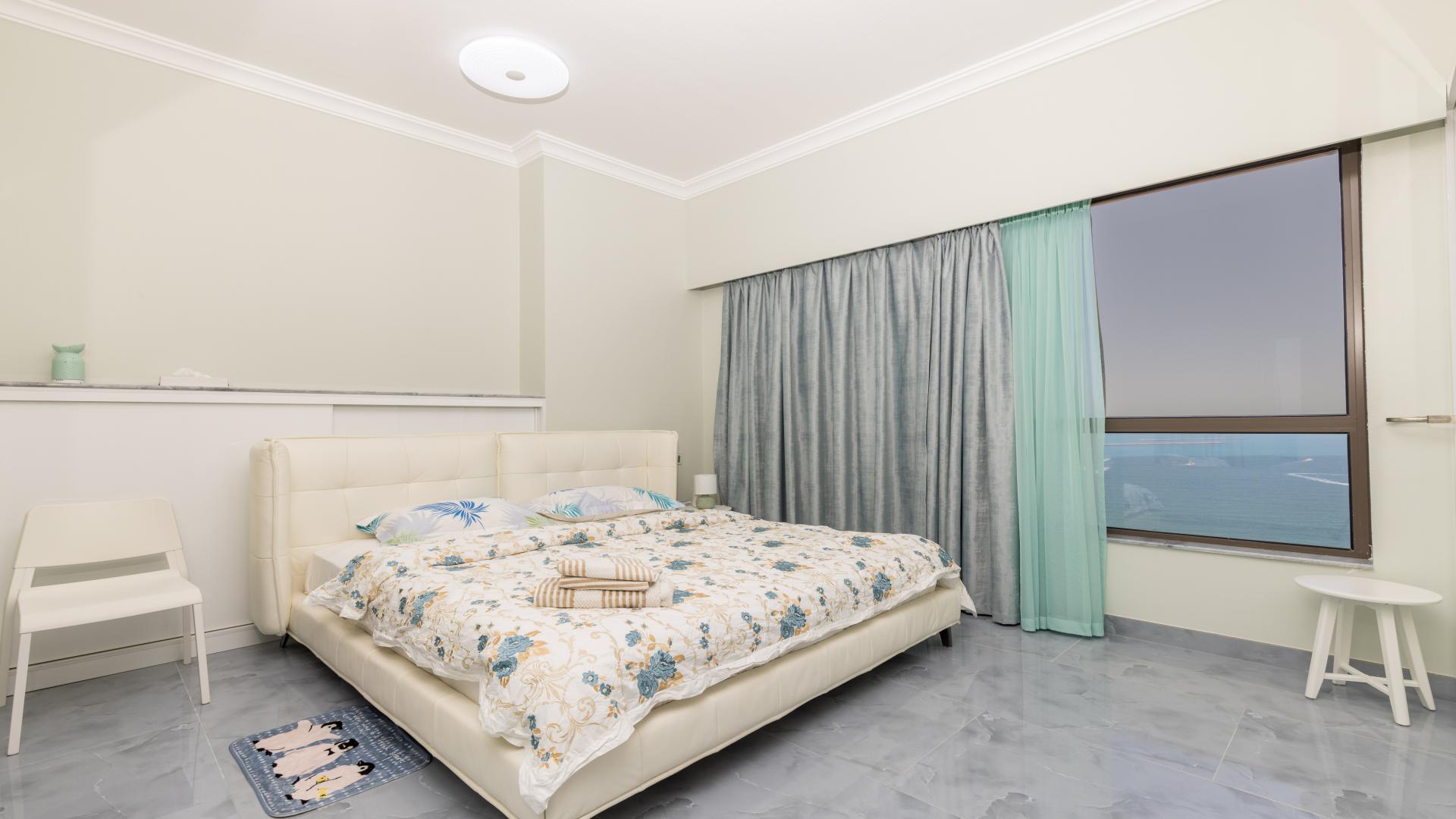 Spacious bedroom in JBR apartment with modern furnishings and large mirrored closet