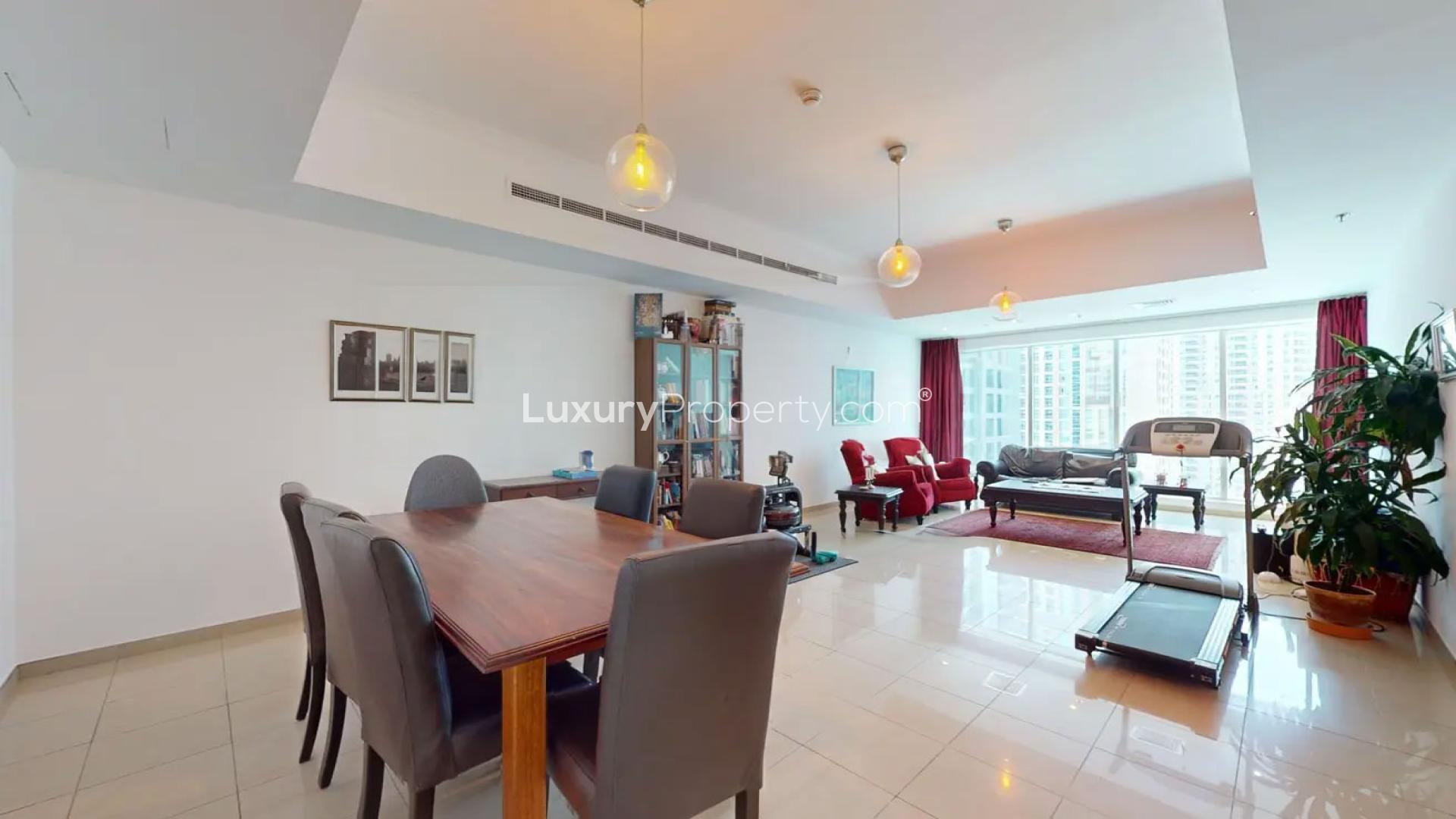 Furnished living room in 2-bed Dubai Marina apartment, Emirates Crown, with red accents and treadmill