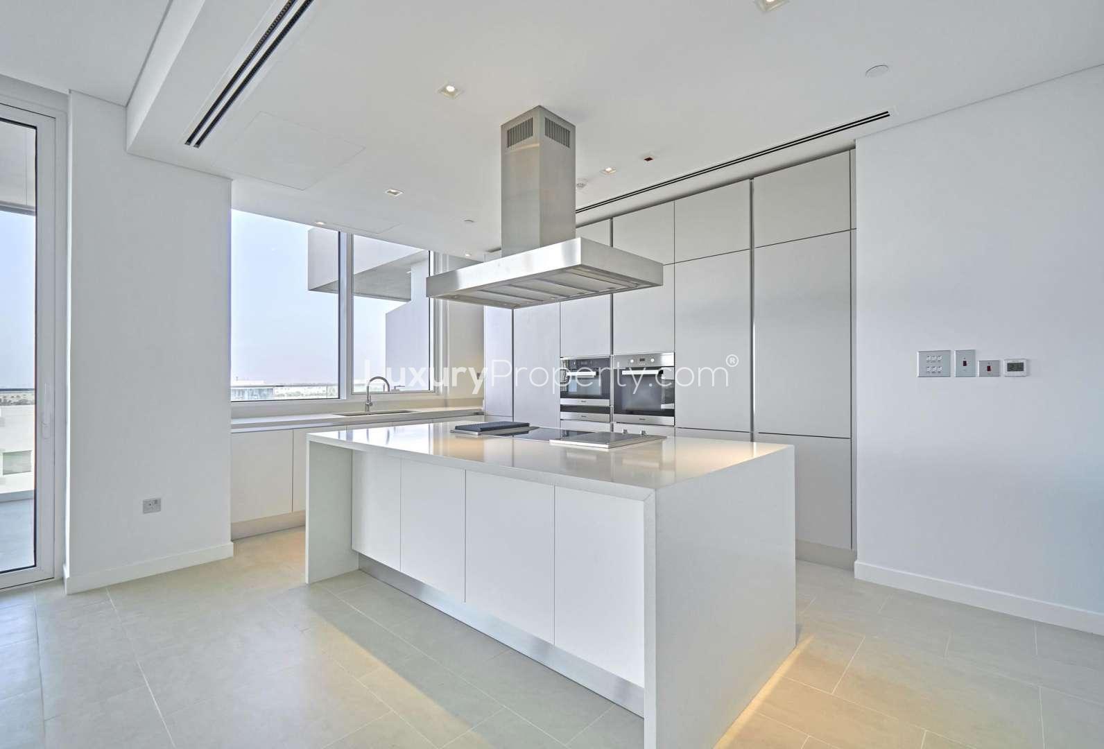 Open-plan living area in Seventh Heaven apartment, Al Barari, with large windows and modern kitchen