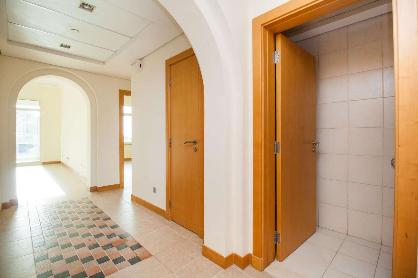 Elegant apartment hallway in Shoreline Residences, Palm Jumeirah with wooden doors and tiled floor