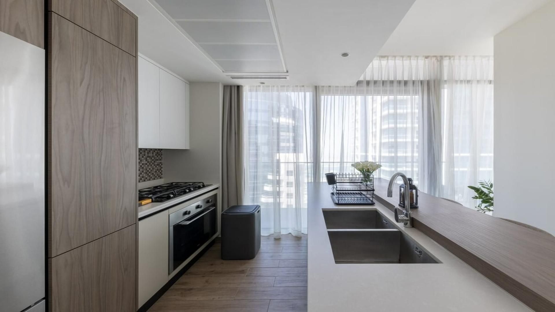 "Spacious furnished living area in high-floor Dubai Marina apartment with city views.",Modern kitchen in high-floor Dubai Marina apartment with city views and sleek design