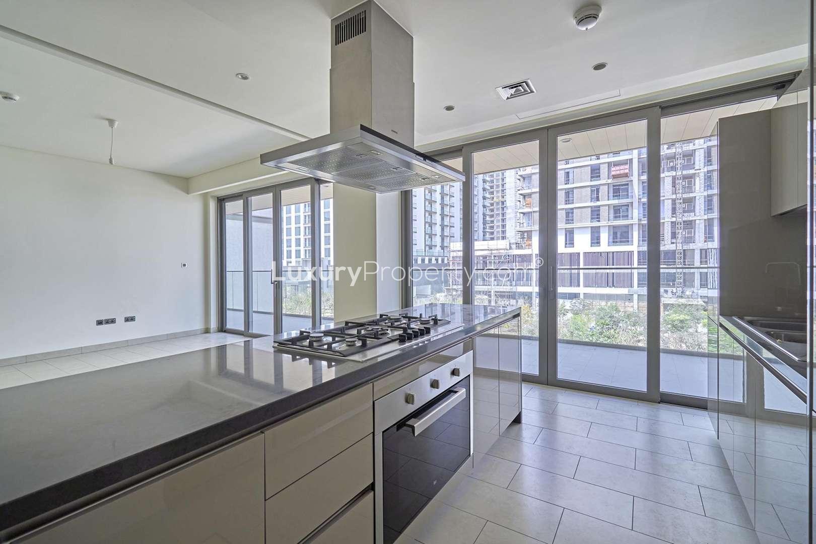 Modern kitchen and living area in Sobha Hartland Greens apartment, Dubai, with large windows