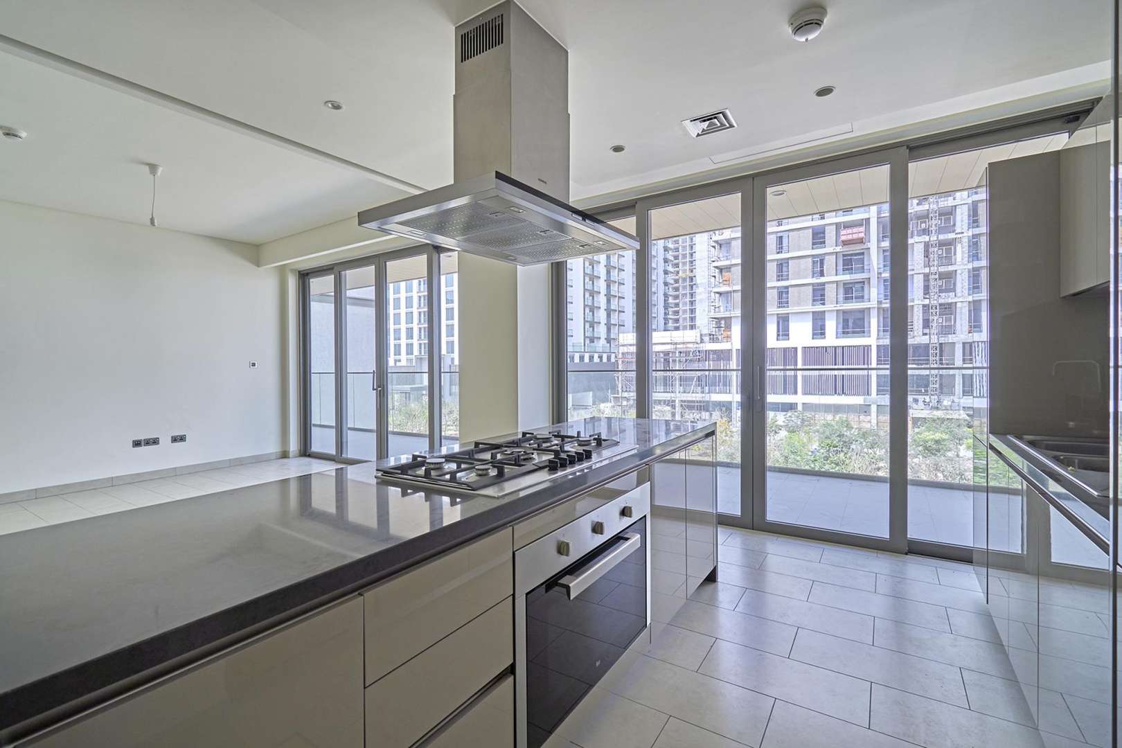 Modern kitchen and living area in Sobha Hartland Greens apartment, Dubai, with large windows
