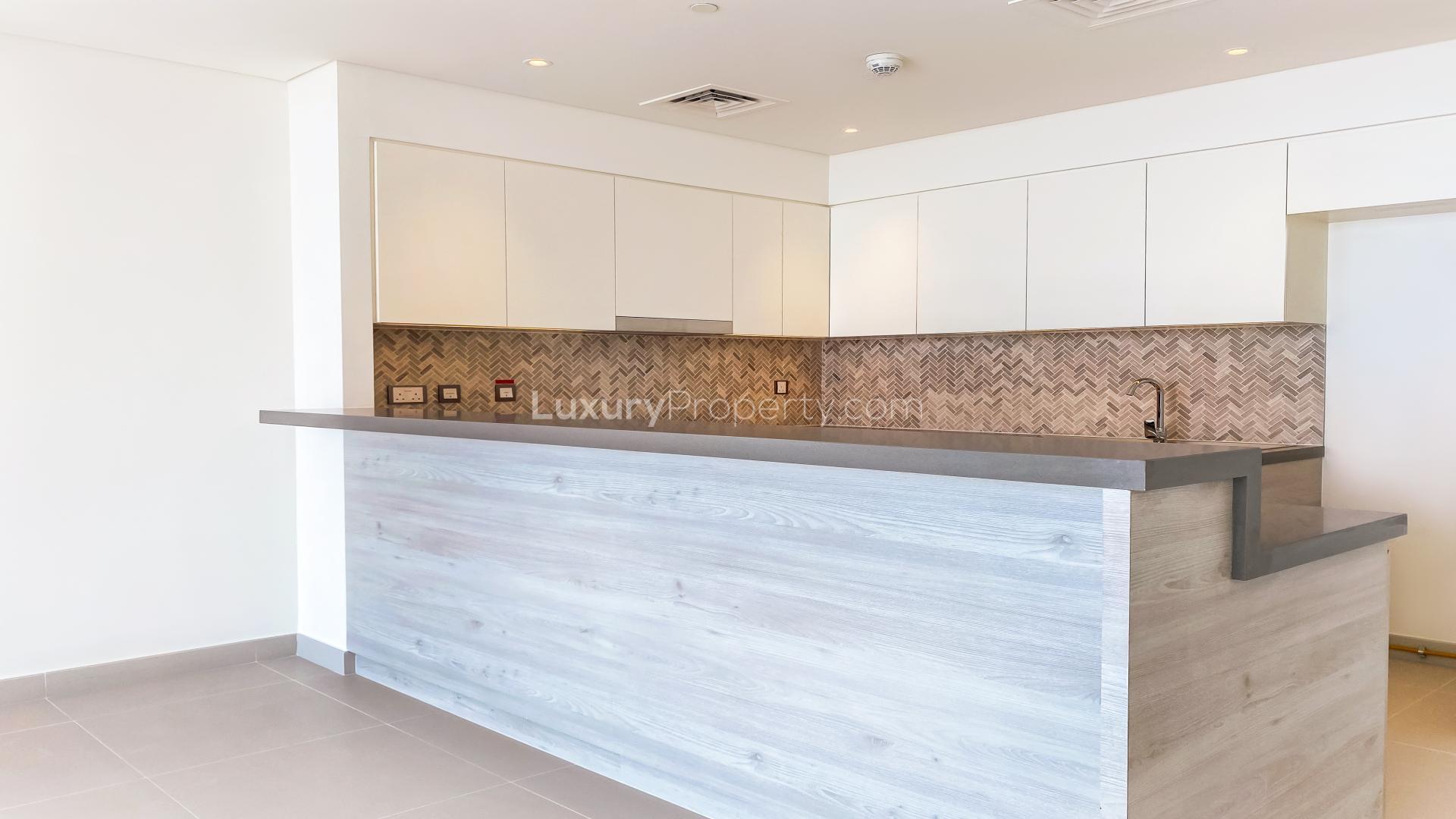 "Spacious living room with floor-to-ceiling windows and Burj Khalifa views in Dubai Creek Harbour.",Modern kitchen in luxurious 2-bedroom apartment, Dubai Creek Harbour, The Cove, Palm Jebel Ali