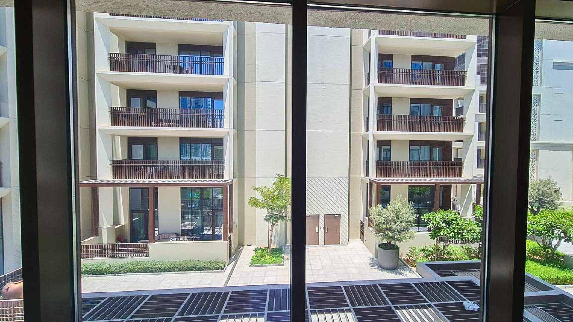 Modern apartment building exterior in Breeze at Dubai Creek Harbour, surrounded by greenery
