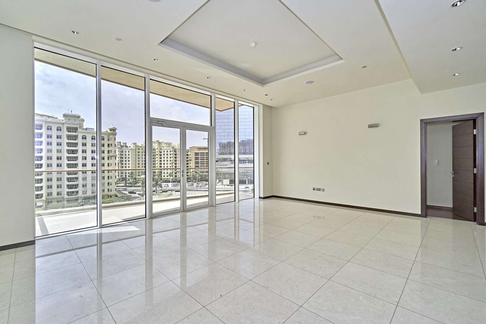 "Spacious balcony view from Amber Tower apartment, Tiara Residences, Palm Jumeirah, Dubai skyline.",Spacious living room with large windows in Amber Tower, Tiara Residences apartment for rent