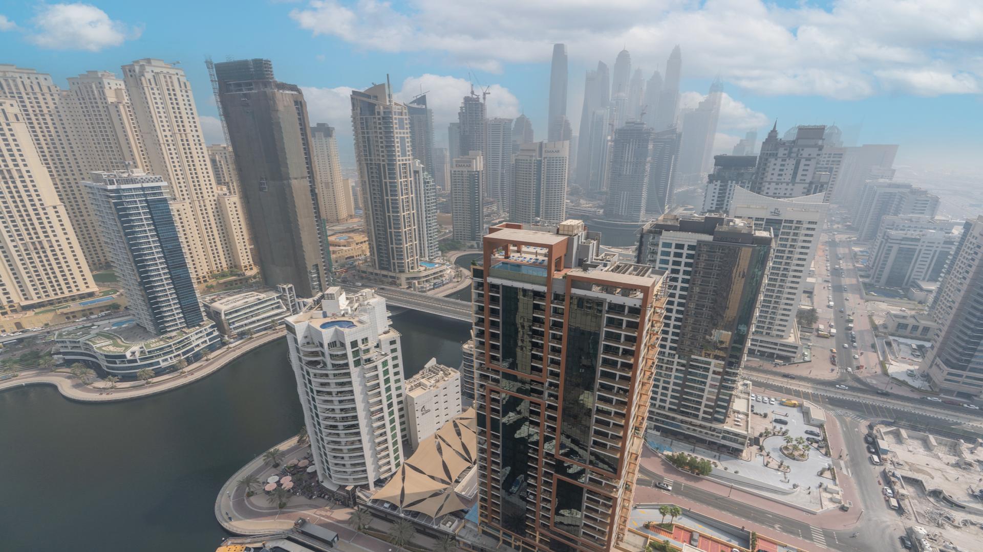 Modern living room in Dubai Marina apartment, featuring elegant furniture and open kitchen layout