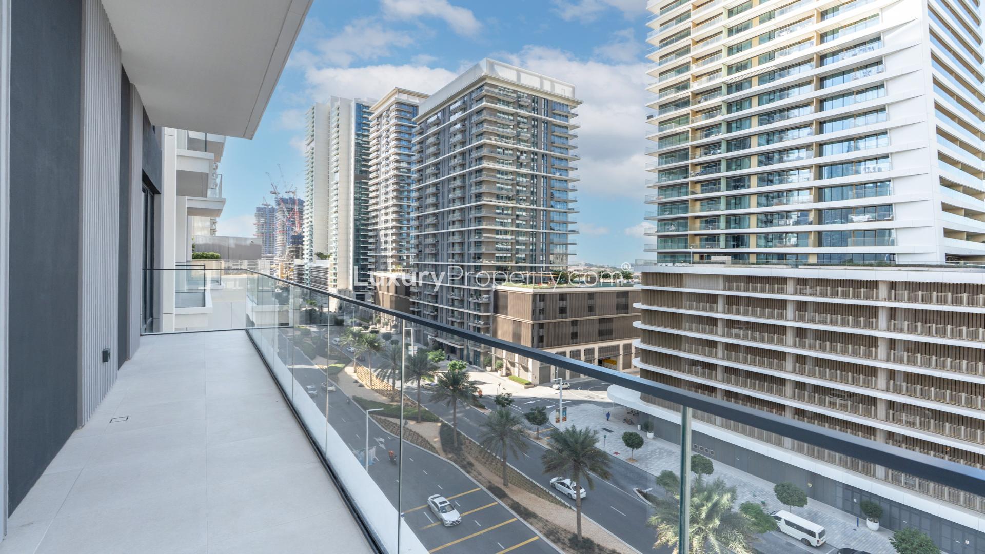 Emaar Beachfront apartment balcony view overlooking modern skyscrapers and city street.