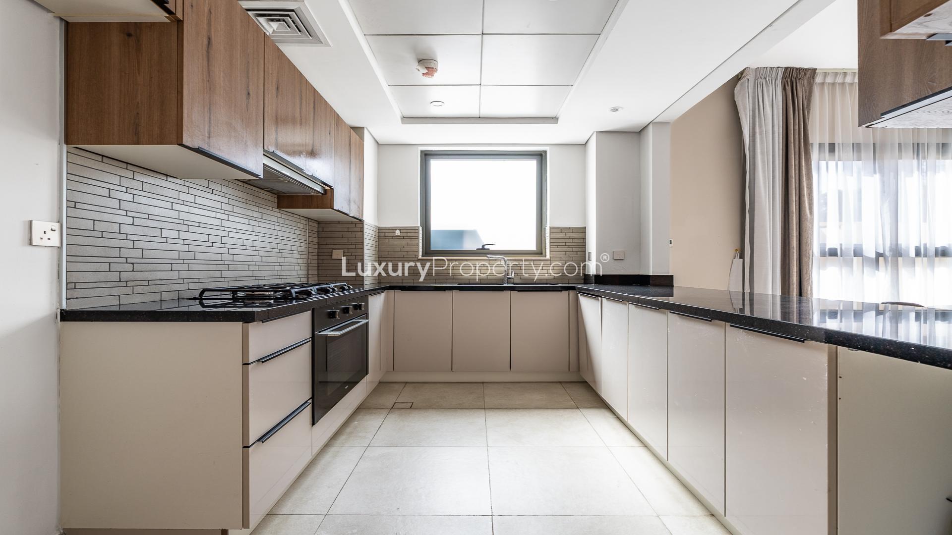 Modern kitchen in 2-bedroom apartment, Eleganz by Danube, JVC. Sleek countertops, wood cabinets