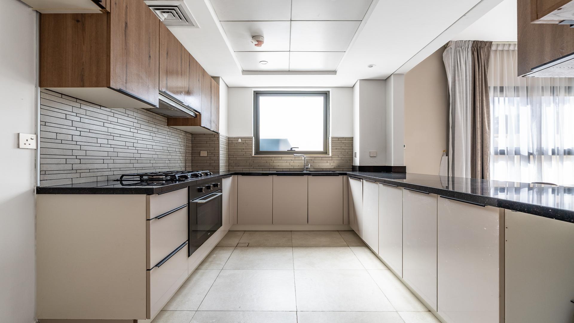 Modern kitchen in 2-bedroom apartment, Eleganz by Danube, JVC. Sleek countertops, wood cabinets