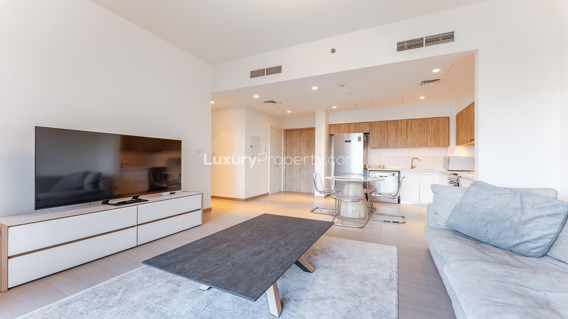 "Park Ridge apartment balcony view overlooking pool and greenery in Dubai Hills Estate.",Modern living room and kitchen area in Dubai Hills Estate apartment, Park Ridge