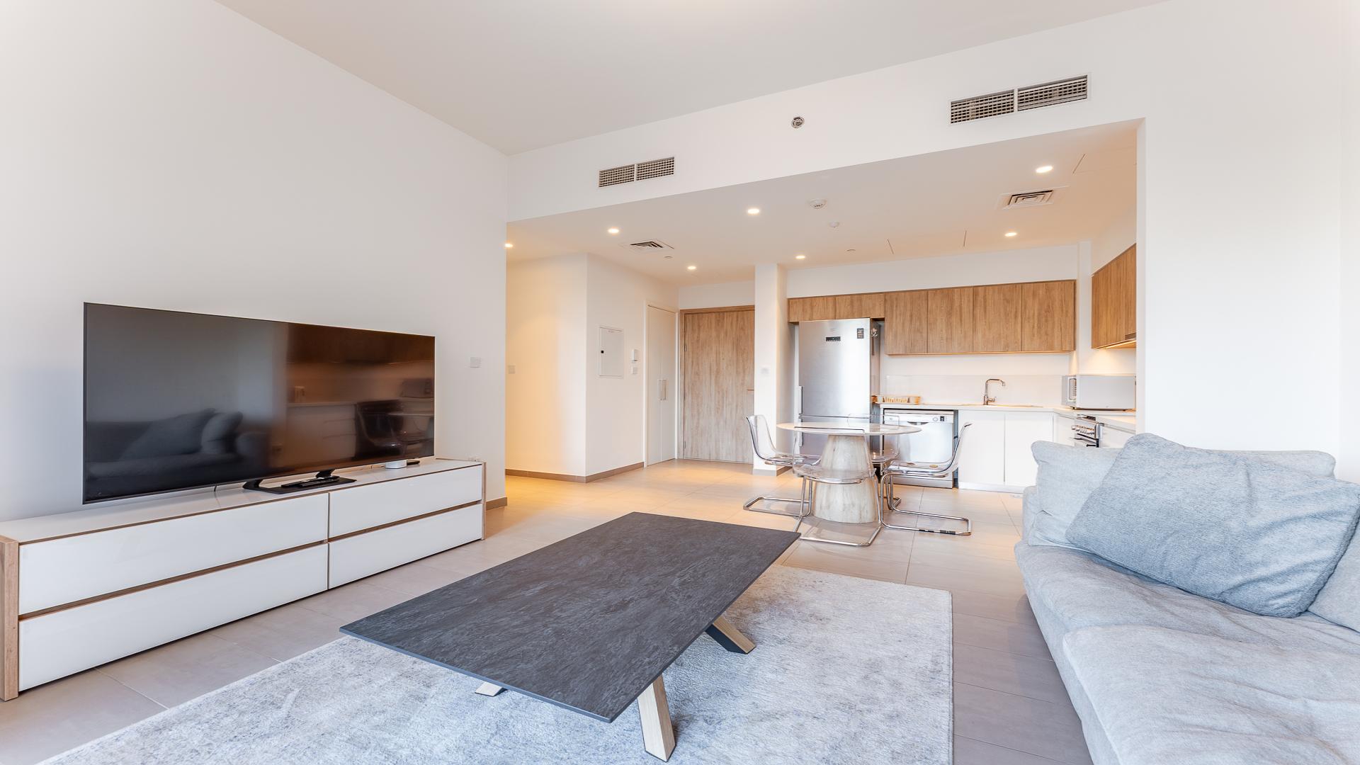 "Park Ridge apartment balcony view overlooking pool and greenery in Dubai Hills Estate.",Modern living room and kitchen area in Dubai Hills Estate apartment, Park Ridge