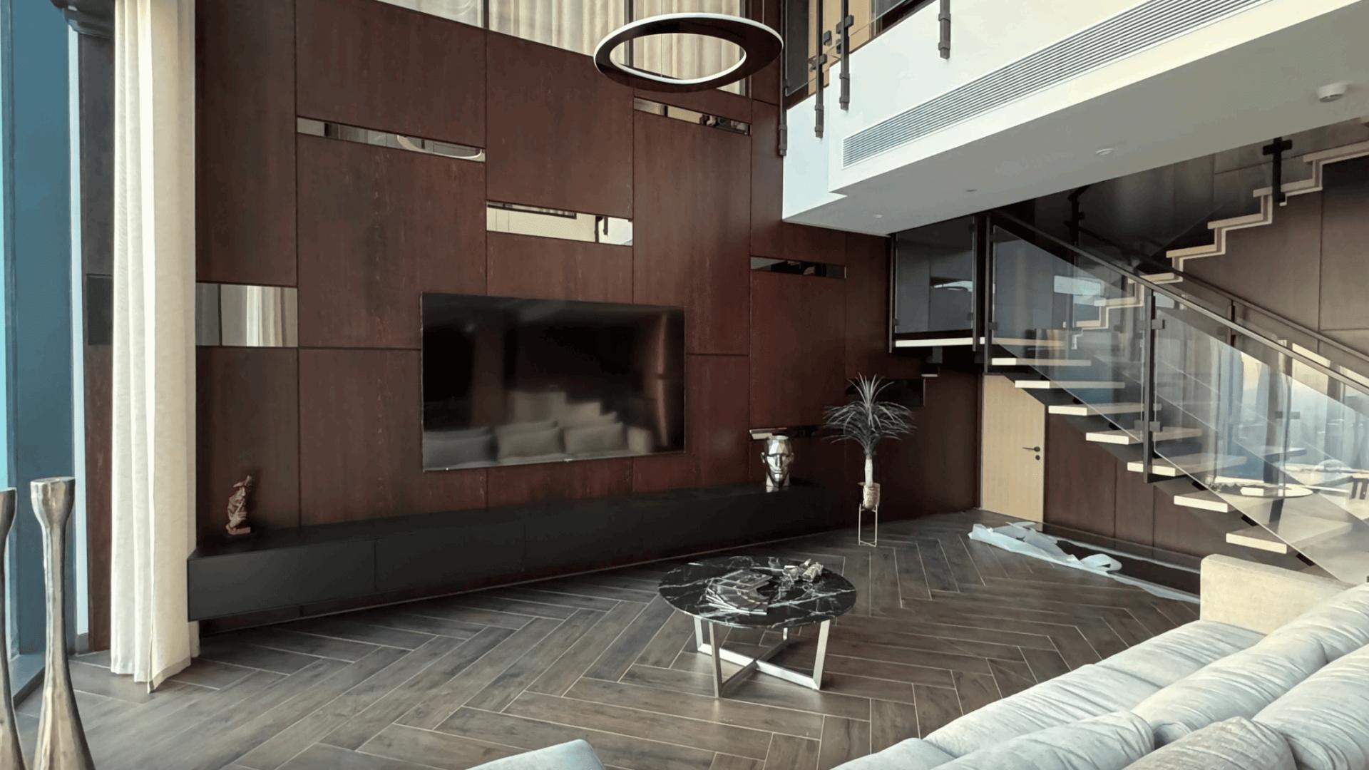 Modern living room in One Zaabeel apartment, featuring sleek staircase and large windows