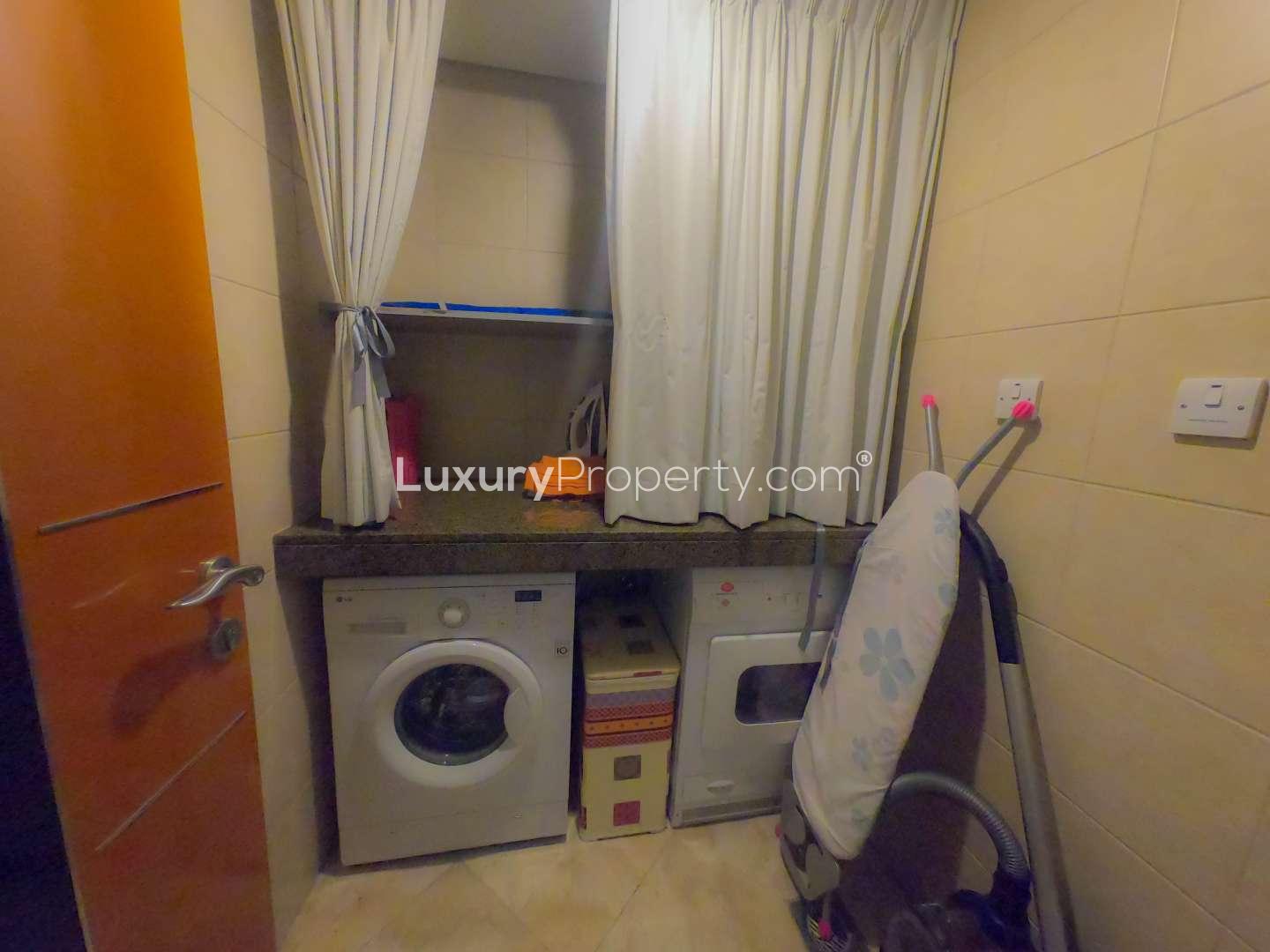 Laundry room with washer, dryer, and ironing board in Al Fattan Marine Tower apartment