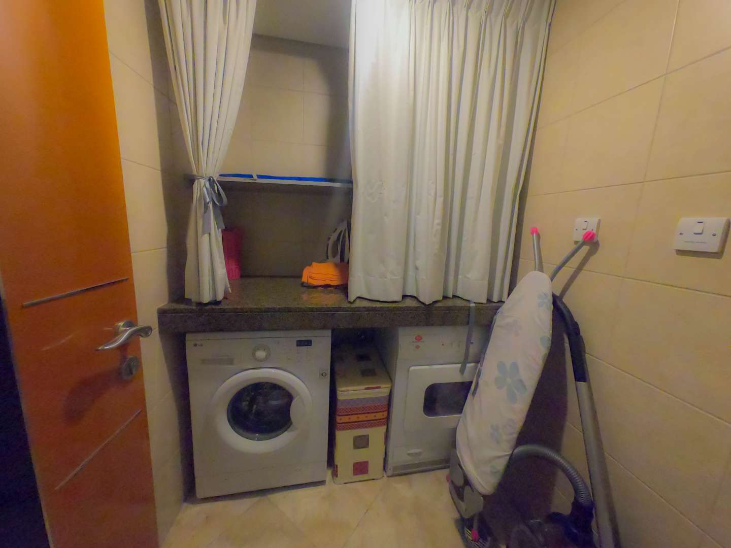 Laundry room with washer, dryer, and ironing board in Al Fattan Marine Tower apartment