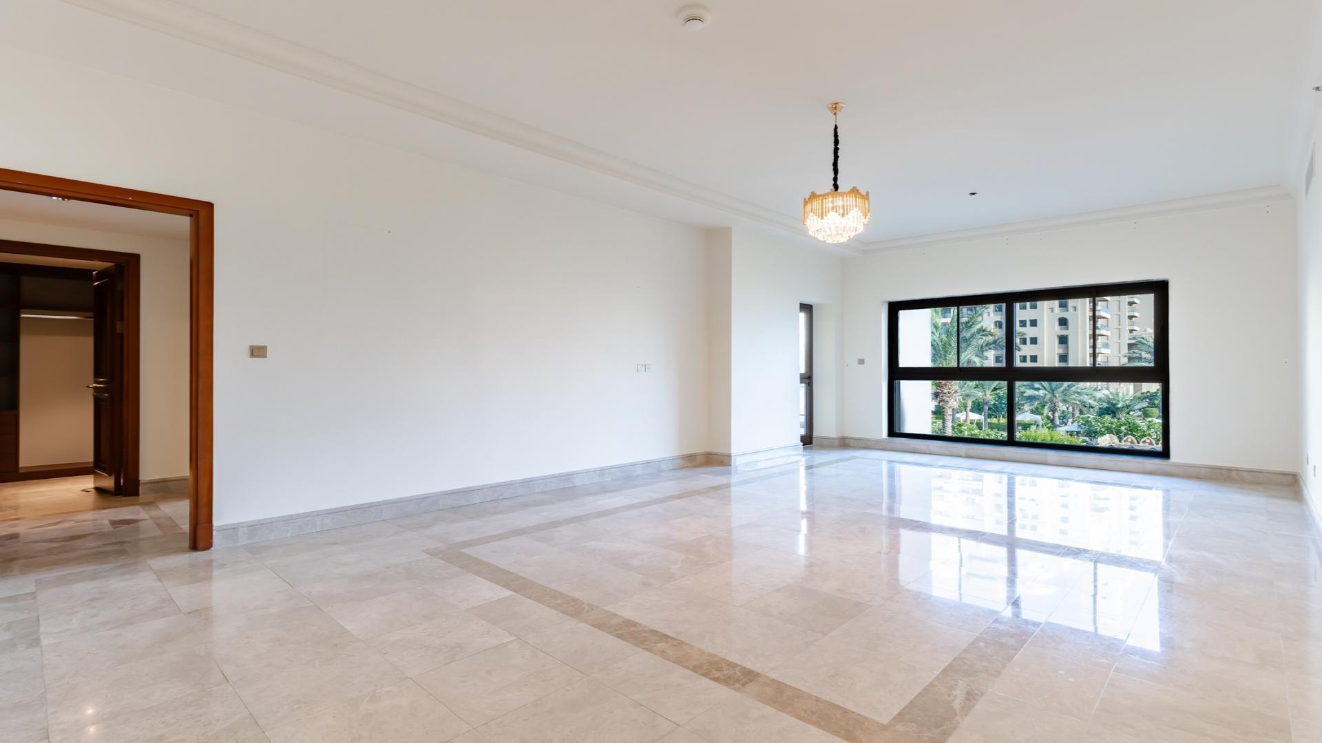 "Spacious Fairmont Palm apartment hallway and kitchen with marble floors, Palm Jumeirah views.",Spacious living room in Fairmont Palm 2-bed apartment with large windows and marble floors