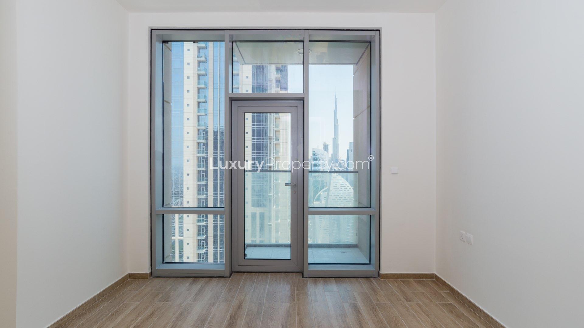 Empty room with wooden flooring and built-in wardrobe in Amna Tower apartment